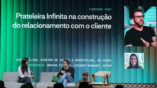 Membros da equipe da Adyen conversam durante evento corporativo com tela de apresentação ao fundo.