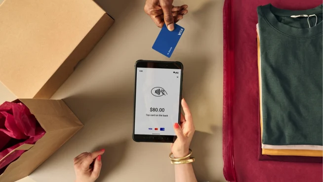 Person tapping a card on a mobile Android device showing an Adyen checkout screen.