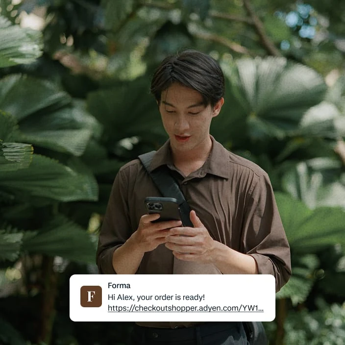 Adyen employee in a brown shirt using a mobile device, with a payment notification for a ready order.