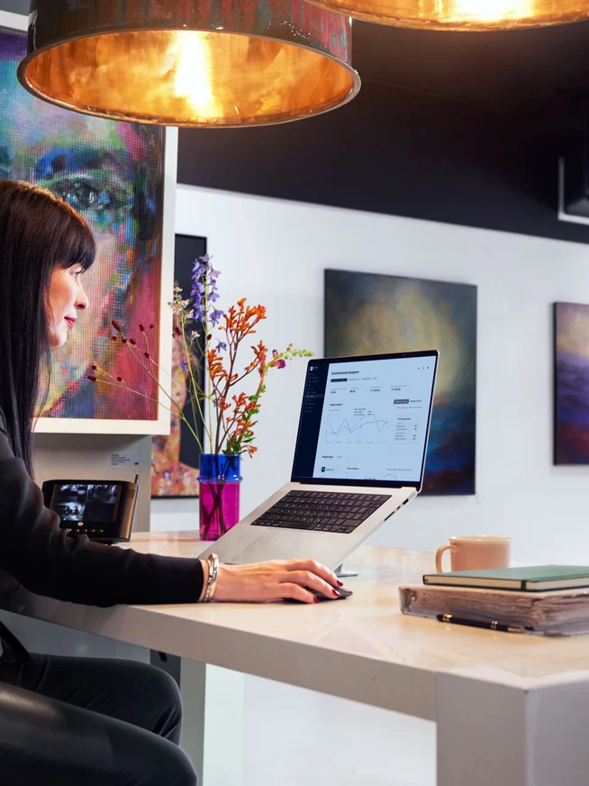 Art gallery employee looking at a payment dashboard on their laptop.