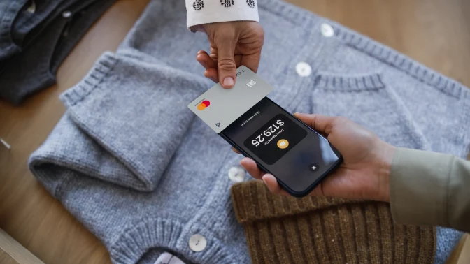 A person makes a payment using a mobile device and a contactless card with Adyen.