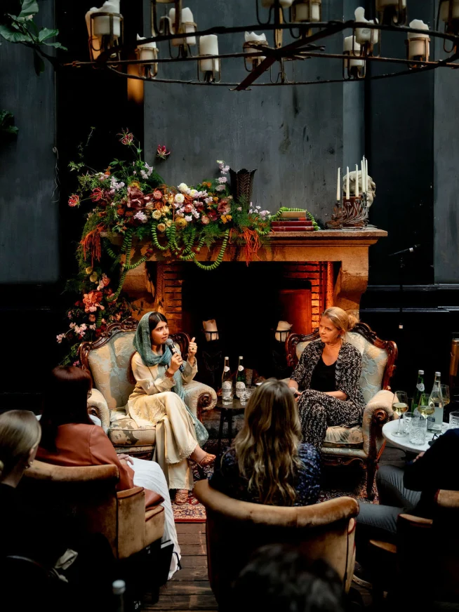 Adyen team members engaged in a discussion in a cozy, decorated indoor setting with floral arrangements and a fireplace.
