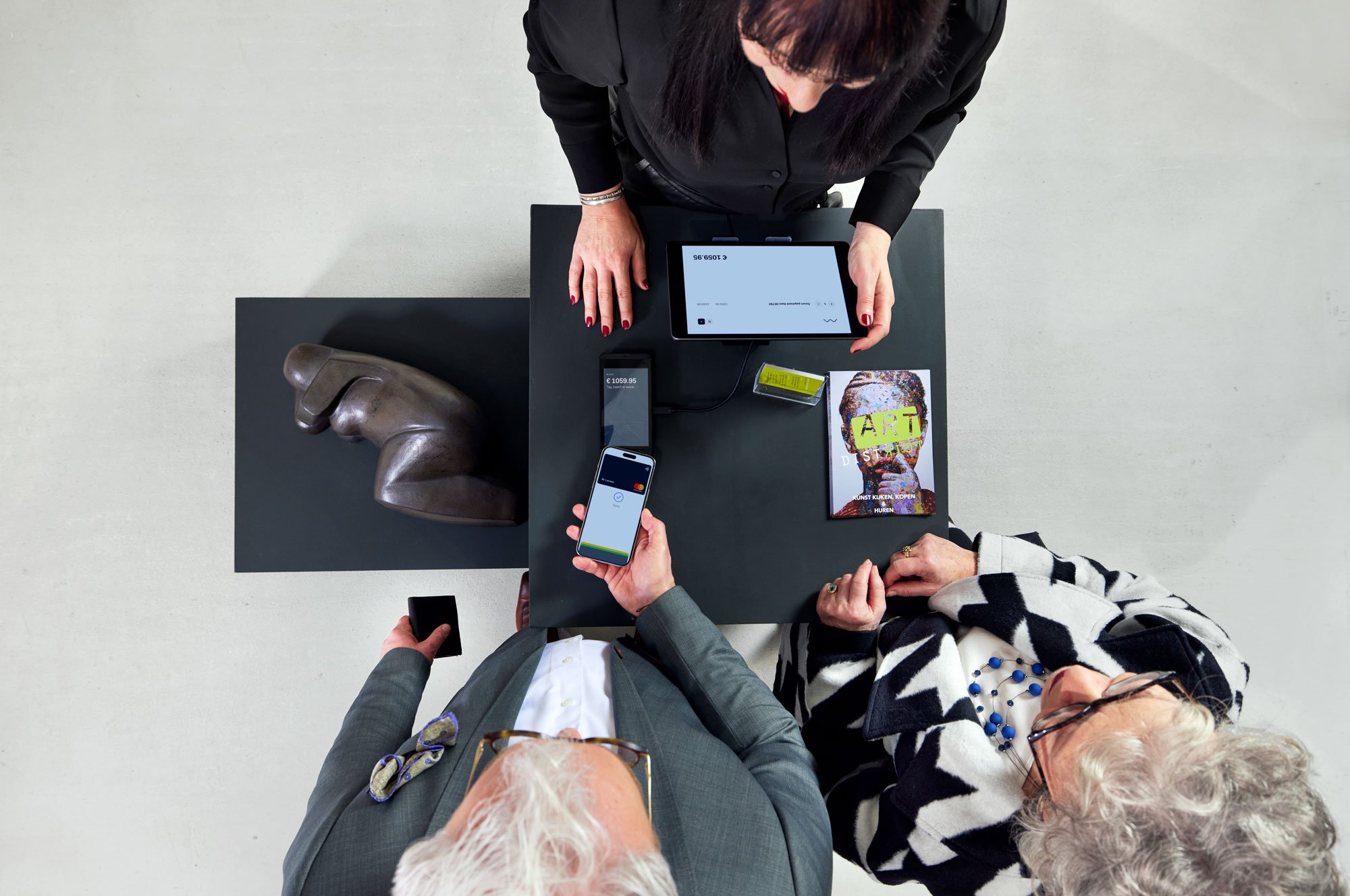 Una pareja pagando en la caja de una galería de arte tocando un teléfono en el terminal S1E de Adyen.