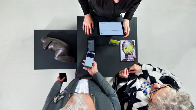Una pareja pagando en la caja de una galería de arte tocando un teléfono en el terminal S1E de Adyen.