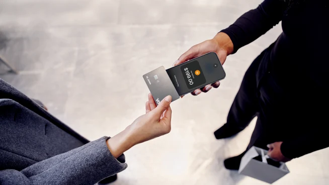 Two people exchanging a contactless payment using an Adyen card and a mobile device.