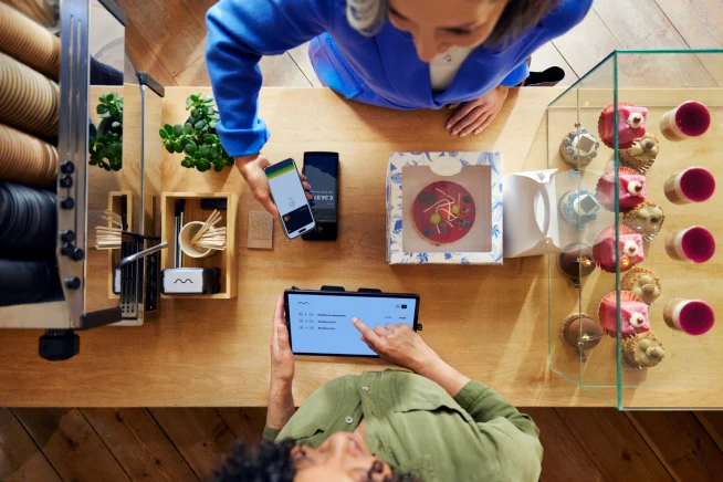 Un cliente in un caffè paga con il telefono utilizzando il terminale S1F2 di Adyen attraverso una piattaforma SaaS per alimenti e bevande