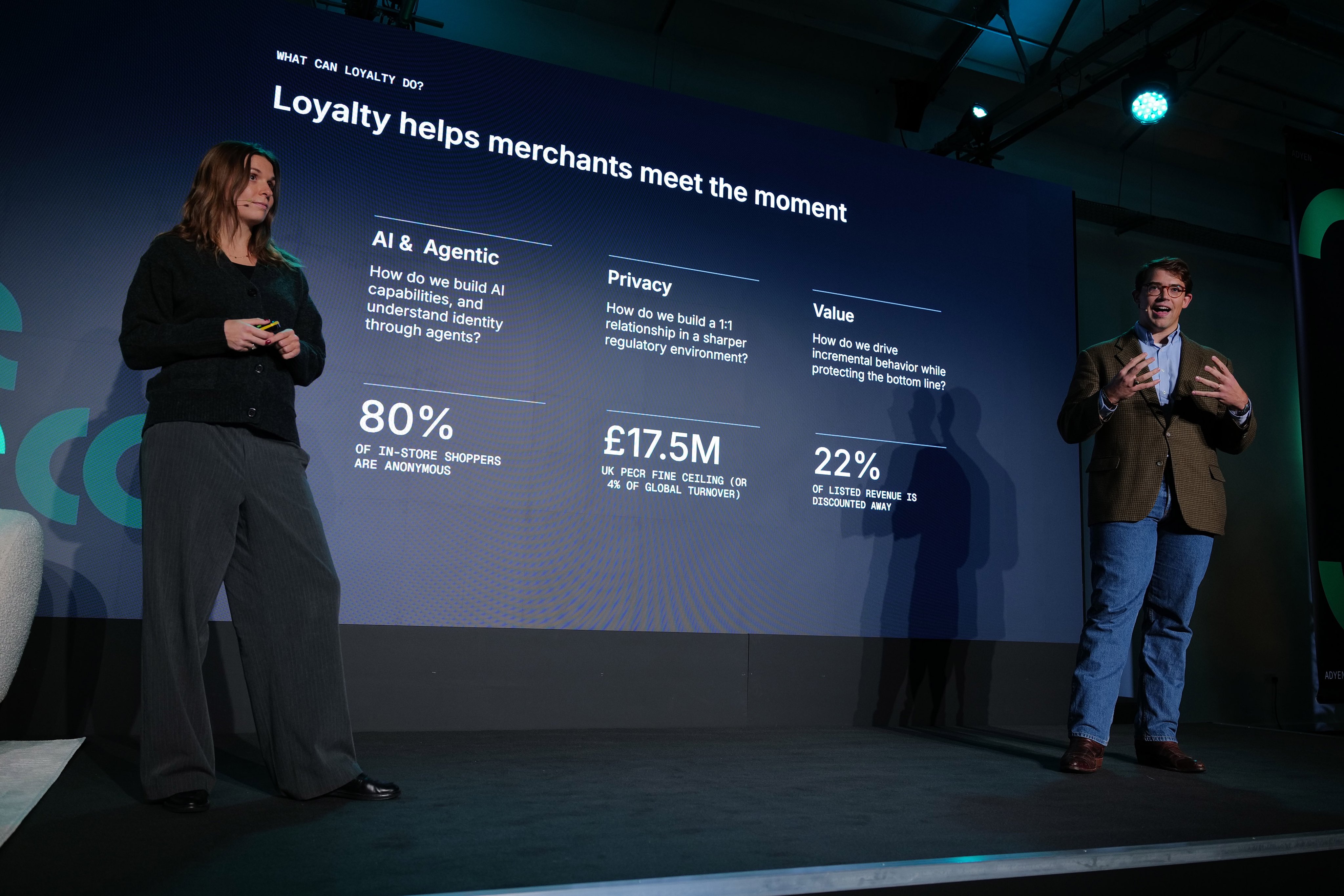 Adyen staff on stage at a corporate event with a presentation screen displaying payment loyalty data