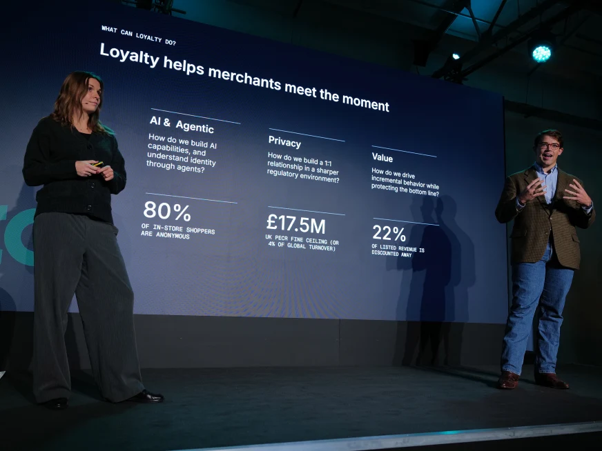 Adyen staff on stage at a corporate event with a presentation screen displaying payment loyalty data