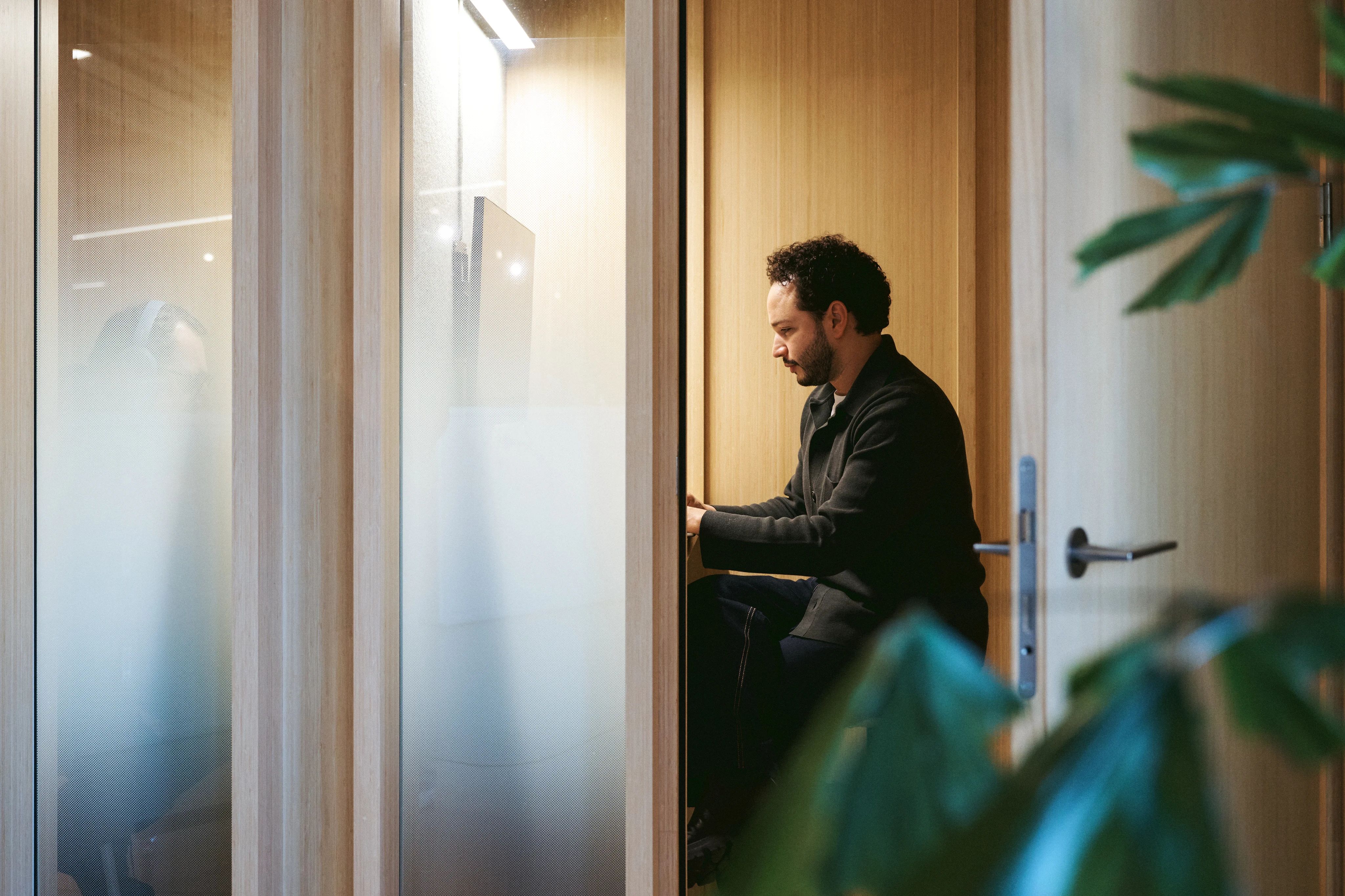man in phone booth at a office behind the laptop