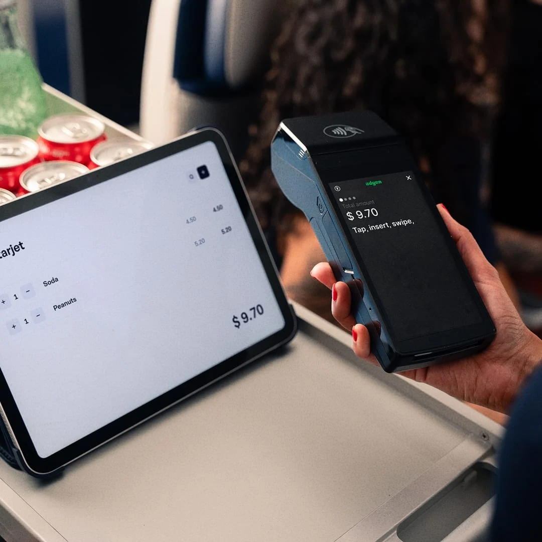 A customer making a contactless payment with an Adyen card terminal while viewing their purchase on a tablet screen.
