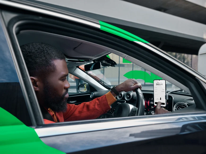 Driver viewing ride hailing app in car