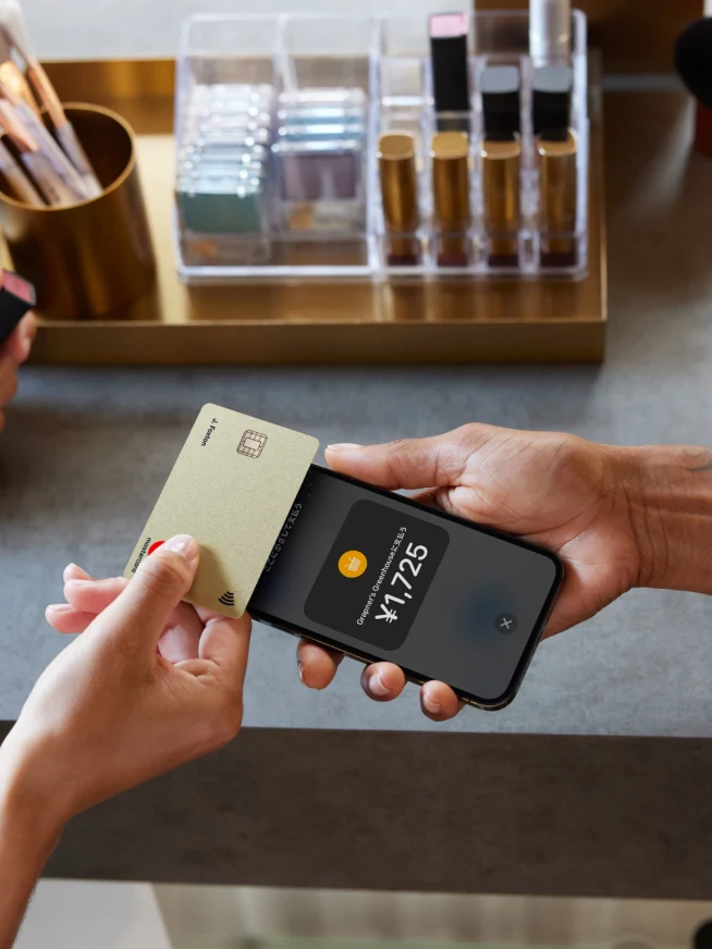 A parson tapping a card on an iPhone with Tap to pay screen in Japanese with an amount in Japanese yen.