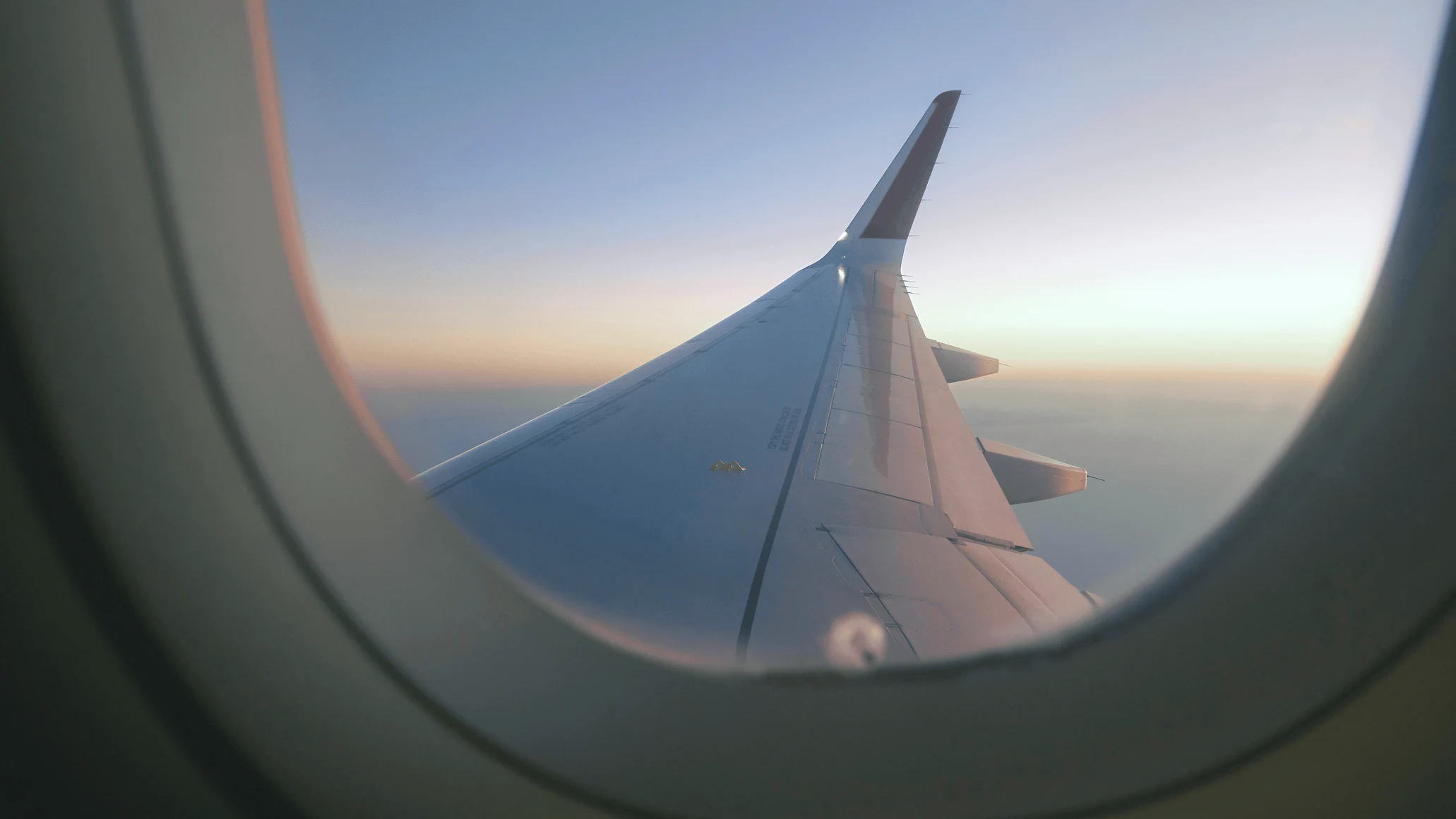 View from airplane window showing wing during sunset flight, capturing a business traveler in transit.