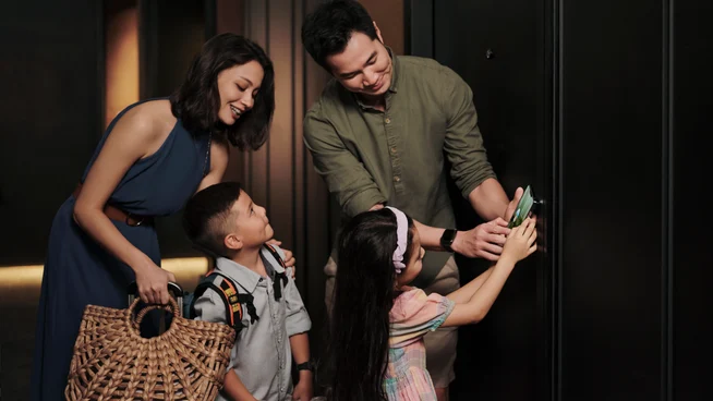 A family with children in a hotel corridor, opening their room with a card, after checking in at the hotel reception.