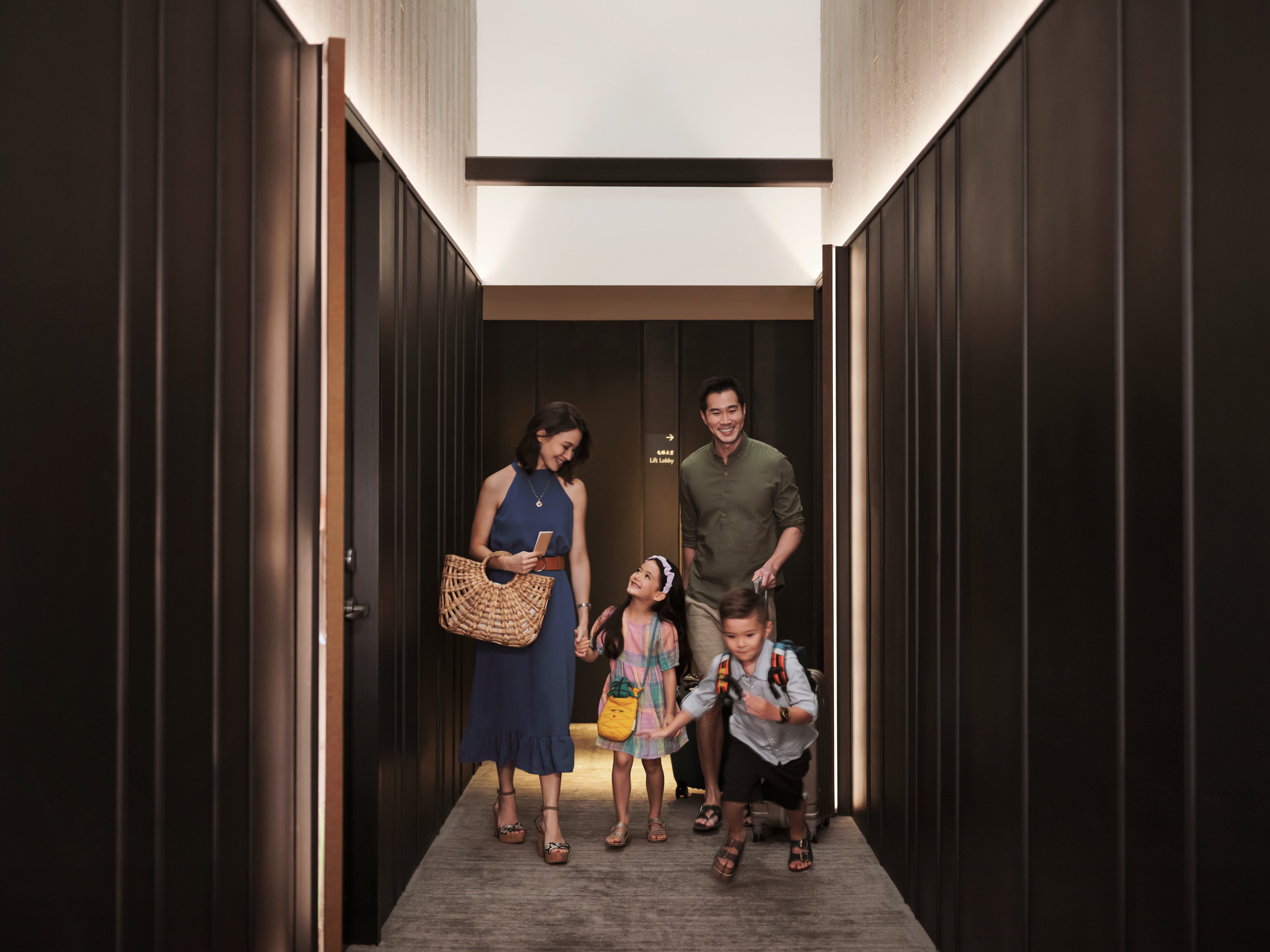 Una familia con hijos, caminando por el pasillo del hotel después de registrarse en su habitación.