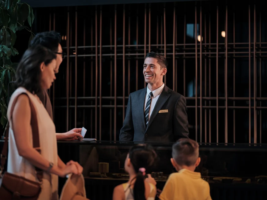 Una familia con niños que se registra en la recepción de un hotel.