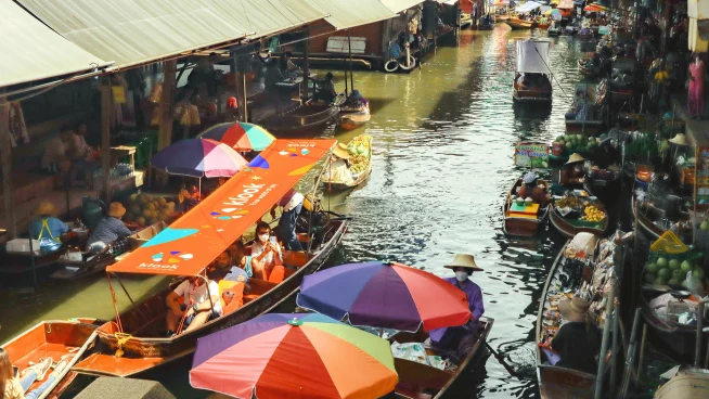 A floating market in Thailand with a Klook boat on the left edge.