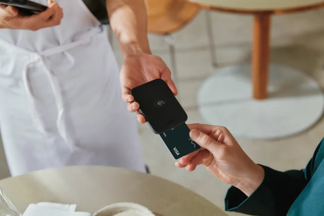 Une femme dans un restaurant payant des repas en tapant une carte VISA sur le terminal NYC1 d'Adyen.