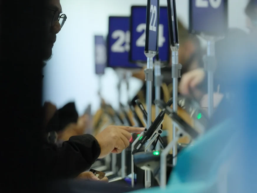 Adyen staff serving at a checkout counter with EFTPOS payment terminals in a retail store.