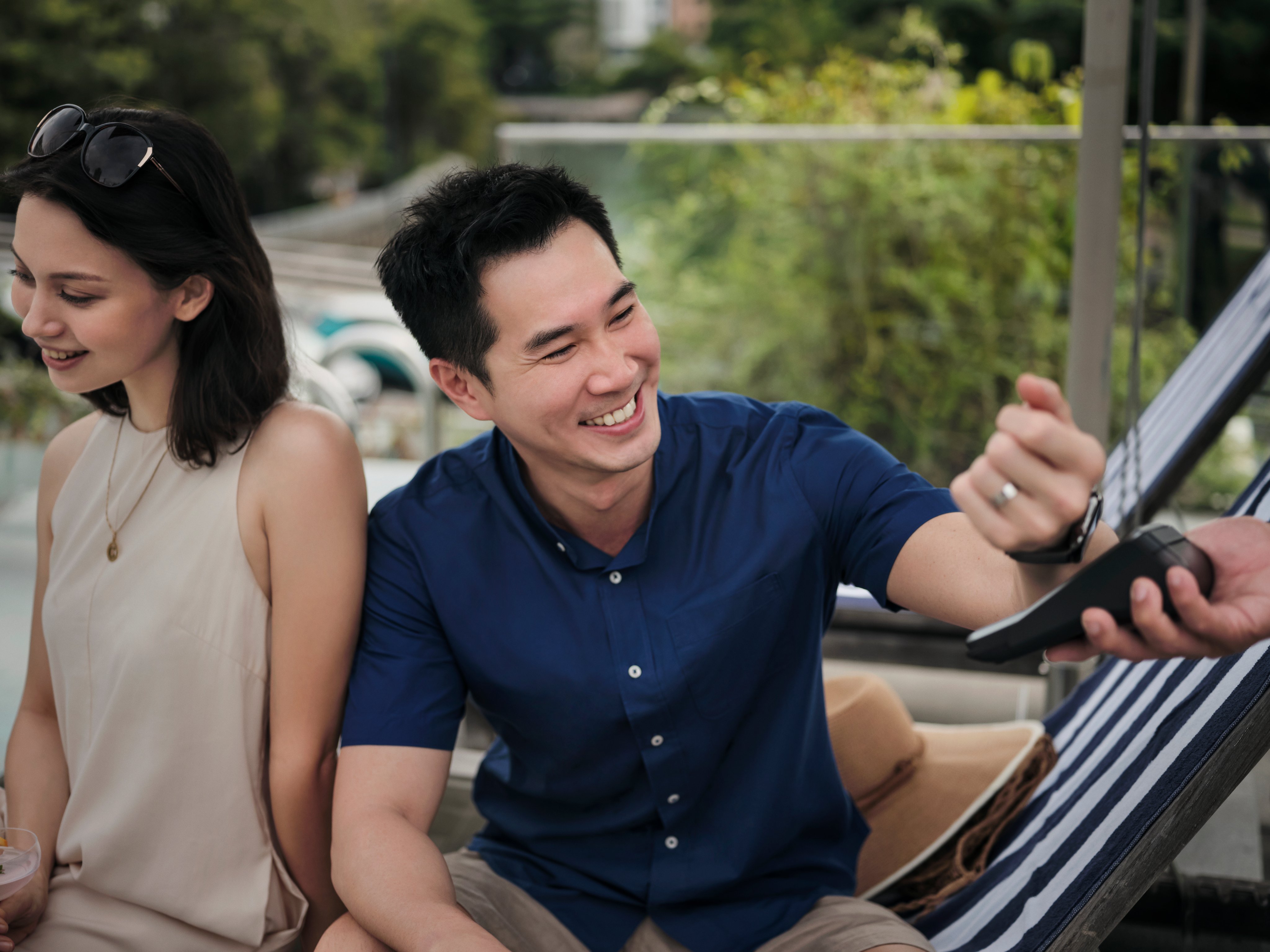 Um casal na piscina de um hotel, pagando bebidas tocando seu smartwatch no terminal da Adyen.