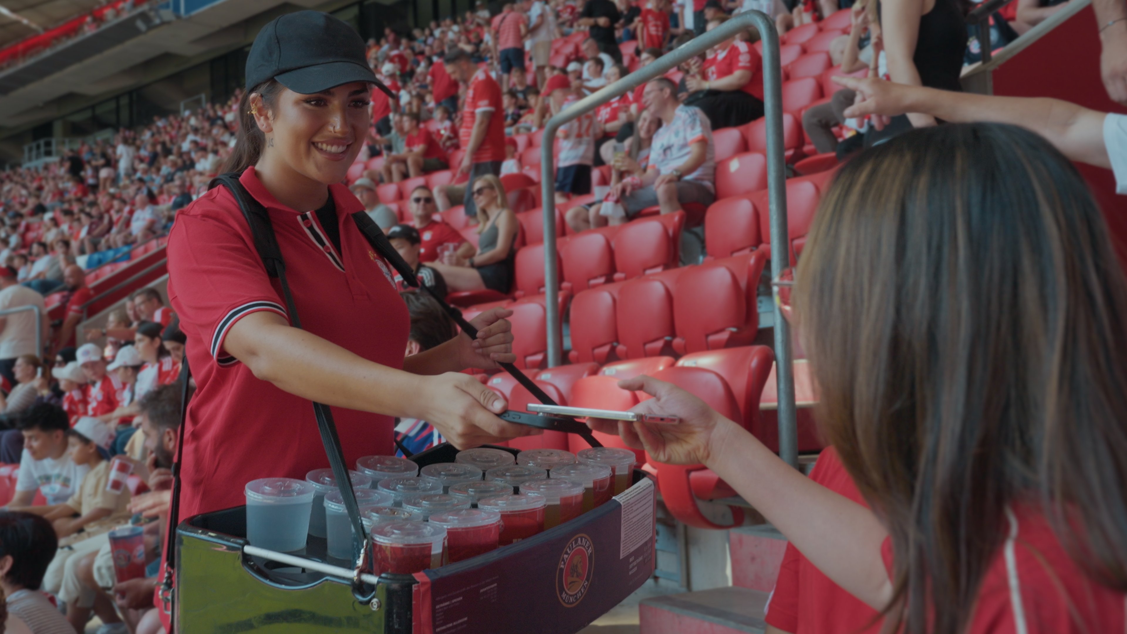 A person purchases drinks from an employee at a stadium concession stand using an Adyen payment terminal.