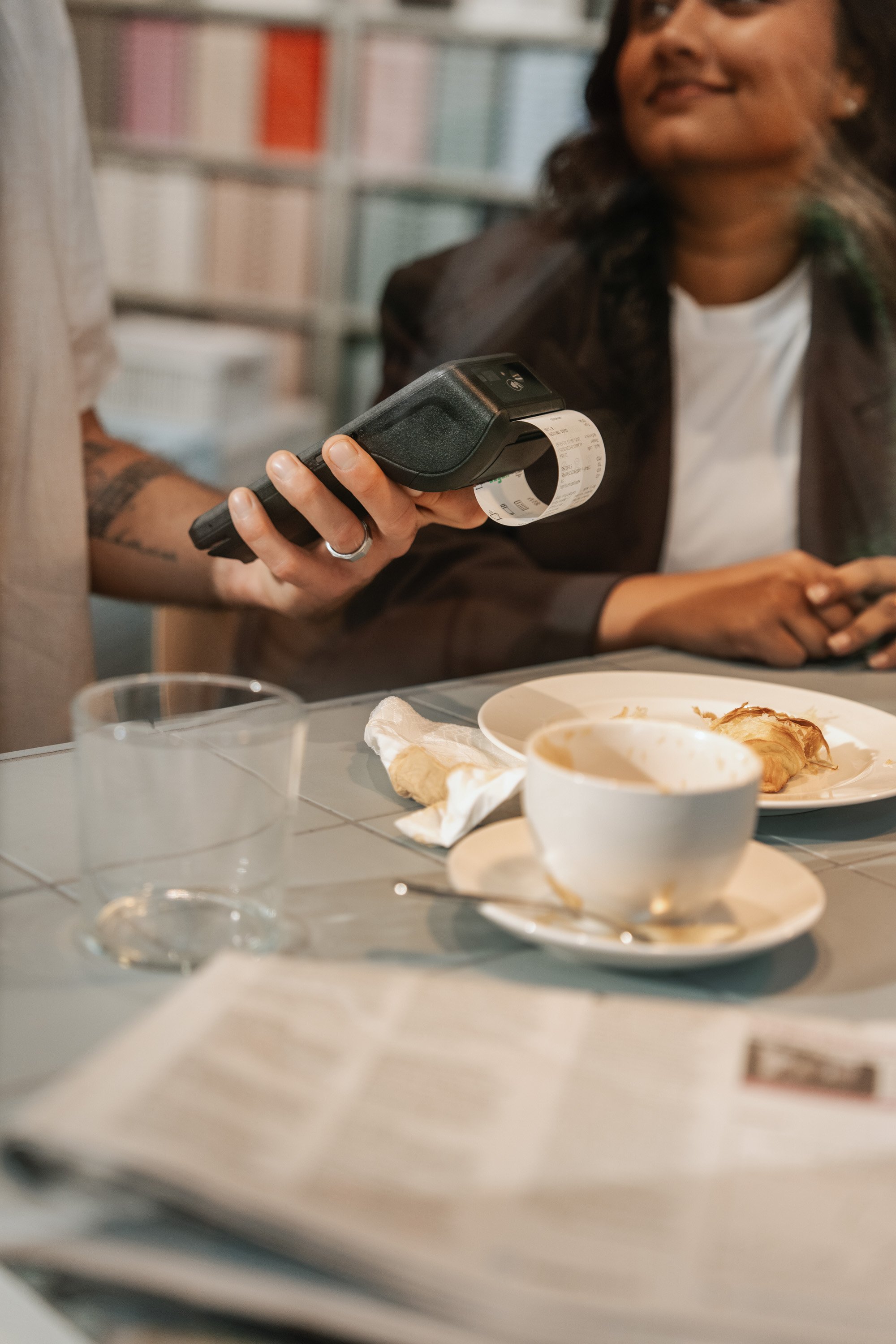 Adyen team members discussing payment with a mobile device at a cafe table