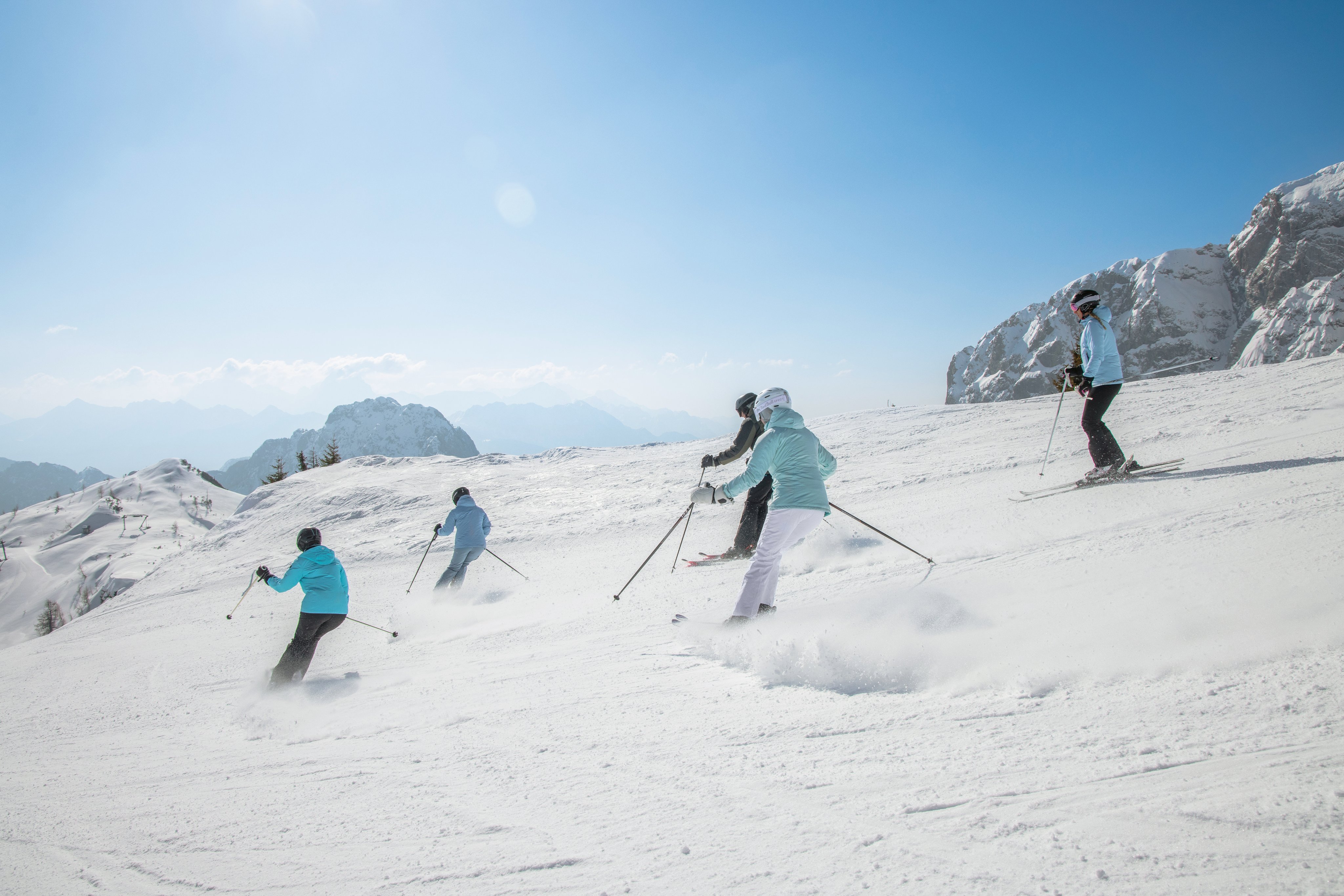 Skifahrer beim sonnigen Wintersport im Alpendzhintergrund, entspannter Premium Cluburlaub