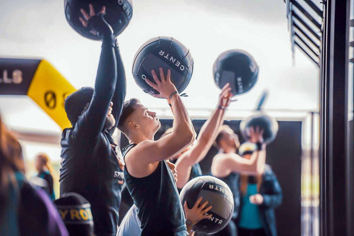 Menschen beim Crossfit-Training mit Medizinbällen im Freien, in einem Premium Cluburlaub.