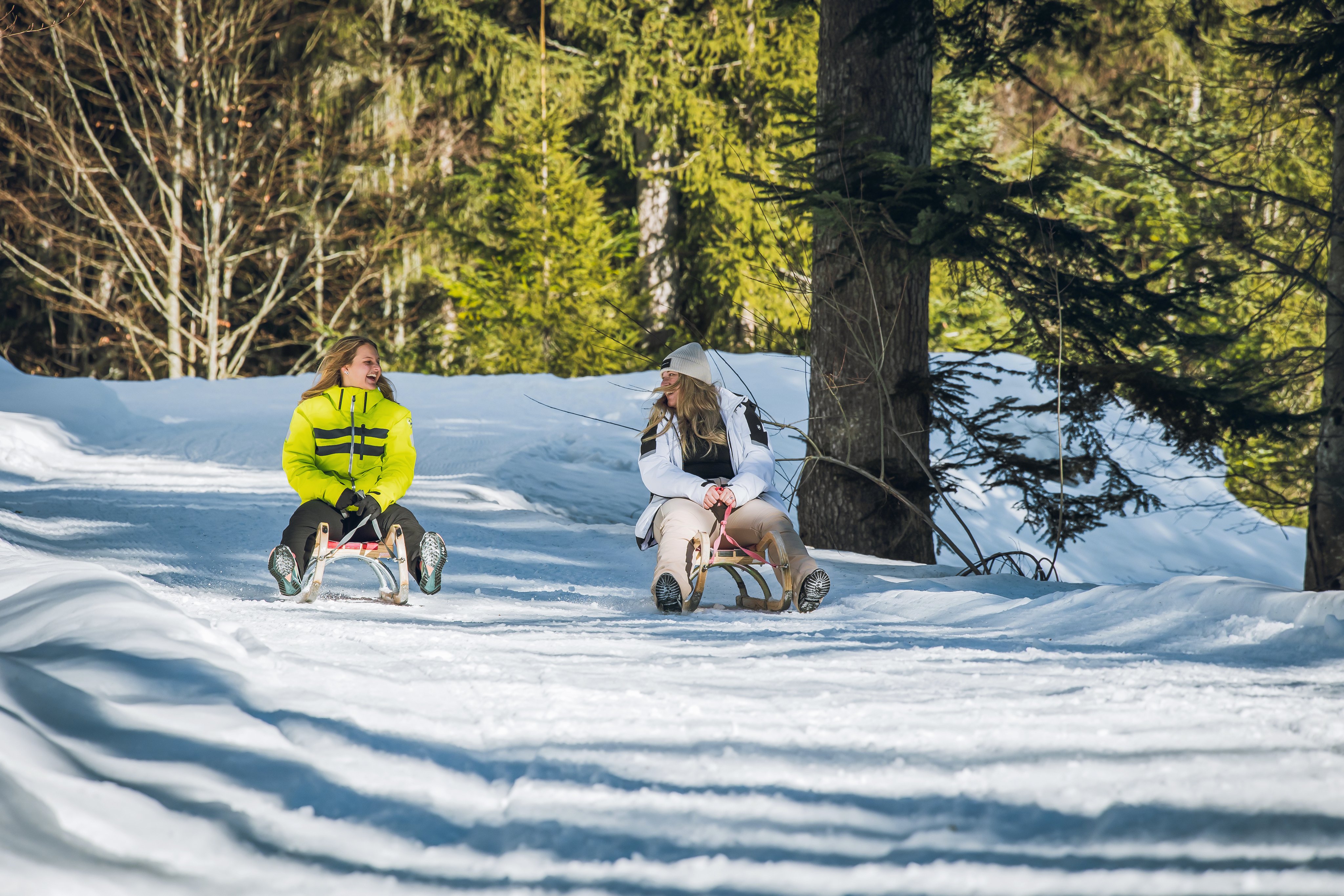 Zwei Kinder ziehen Schlitten im verschneiten Wald bei Aldiana ultimativem Winterurlaub