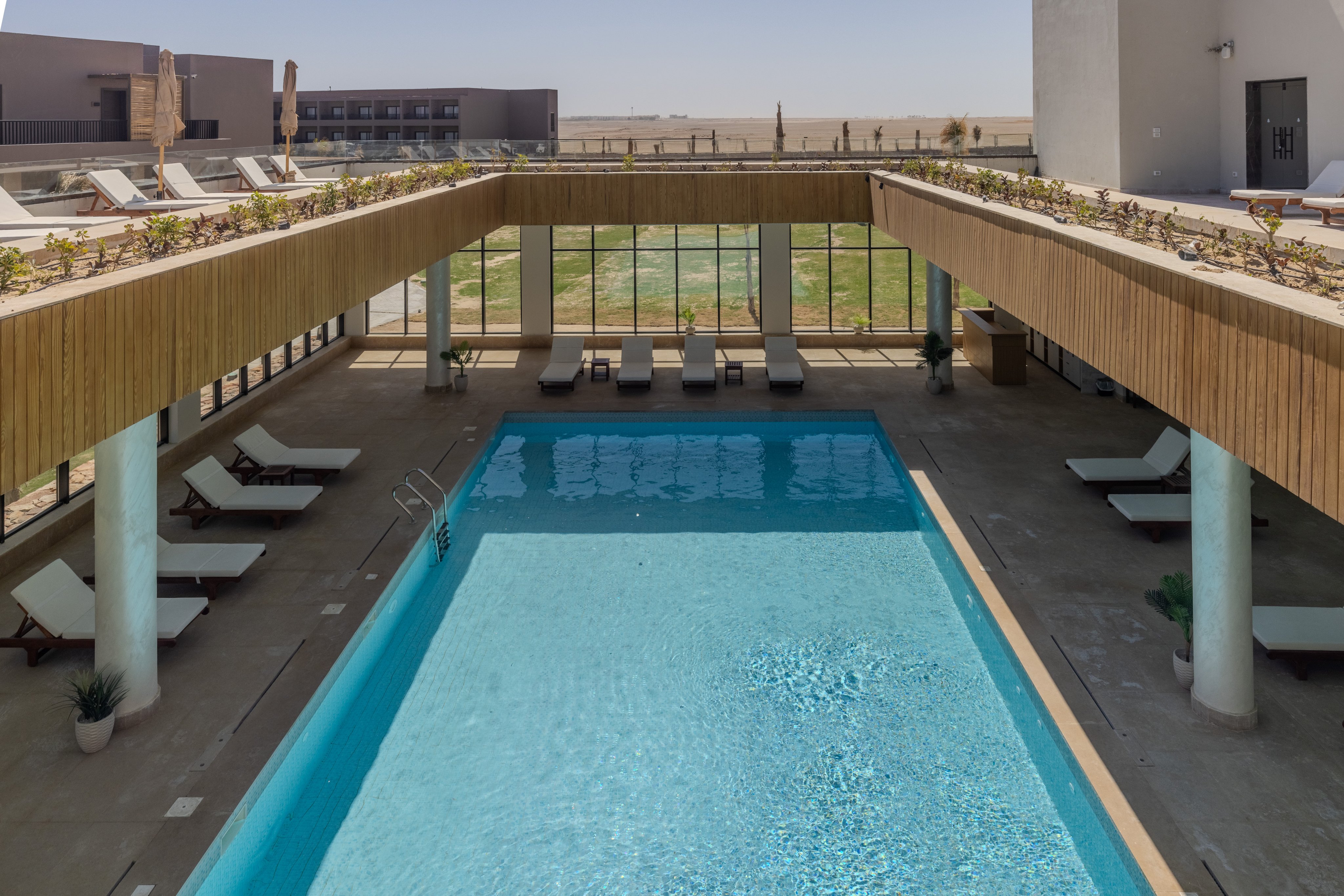 Entspannter Hotelpoolbereich mit Liegen und Blick auf den Himmel.