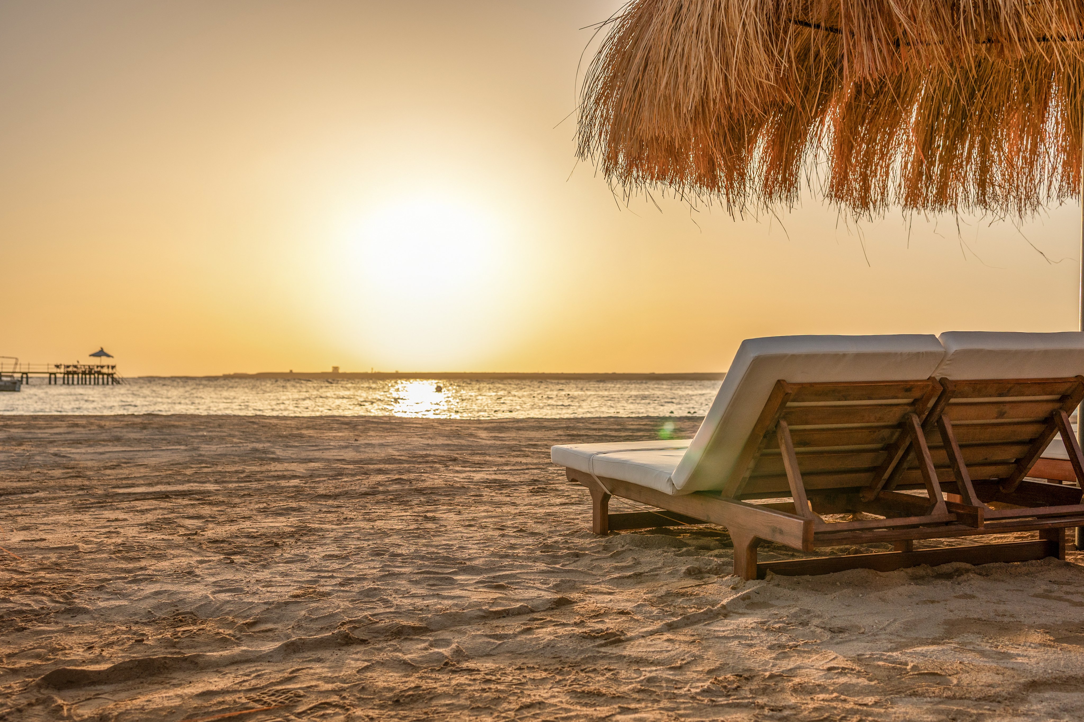 Entspannung am Strand bei Sonnenuntergang mit Liegen und Palmen bei Aldiana.