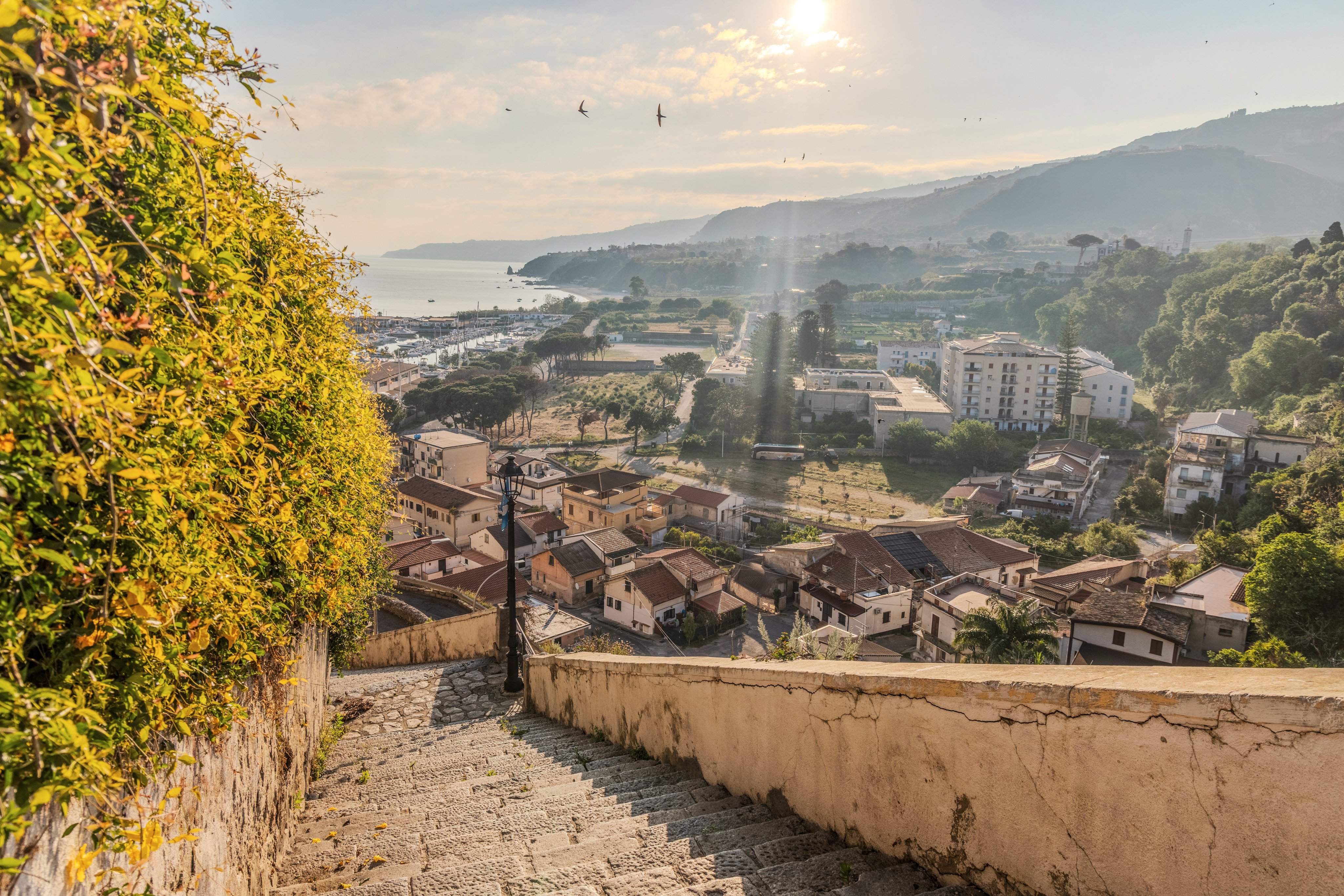 Blick auf eine malerische Küstenstadt mit Berg im Hintergrund bei Sonnenlicht, idealer Ort für Premium Cluburlaub