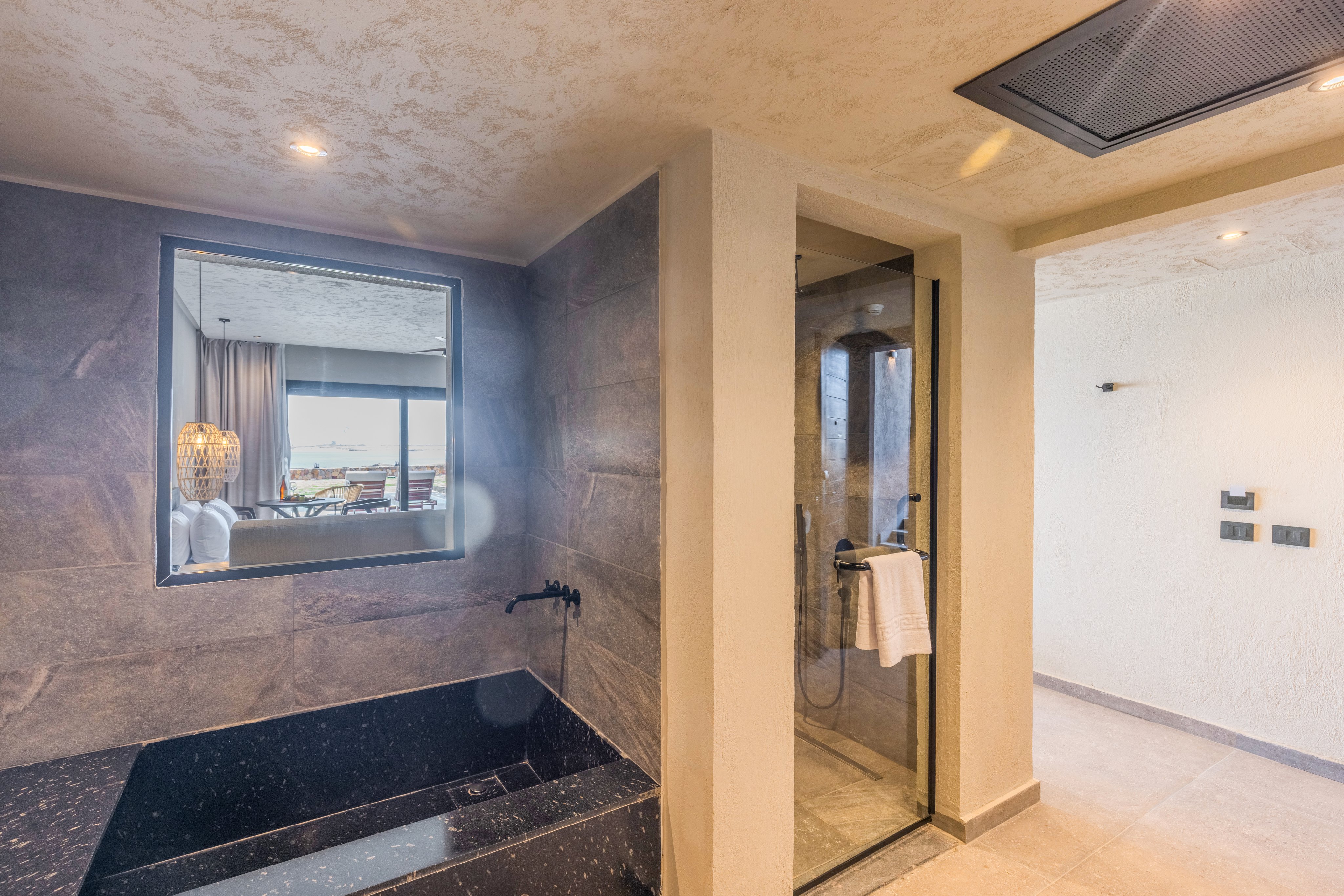 Blick in ein modernes Badezimmer mit Dusche und Spiegel, gemütliches Hotelzimmer im Hintergrund