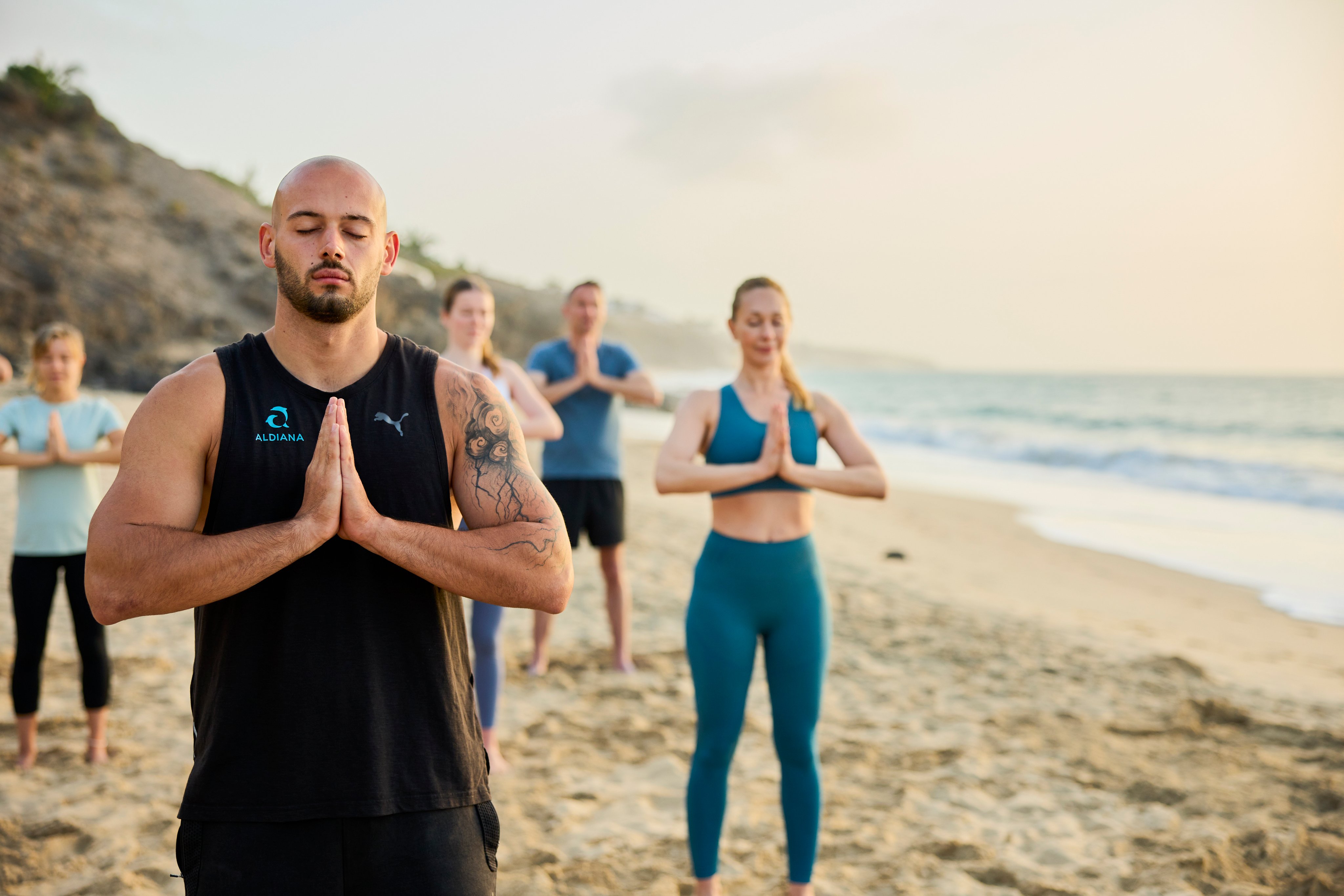 Teilnehmer beim Yoga im Premium Cluburlaub von Aldiana am Strand, entspannte Atmosphäre
