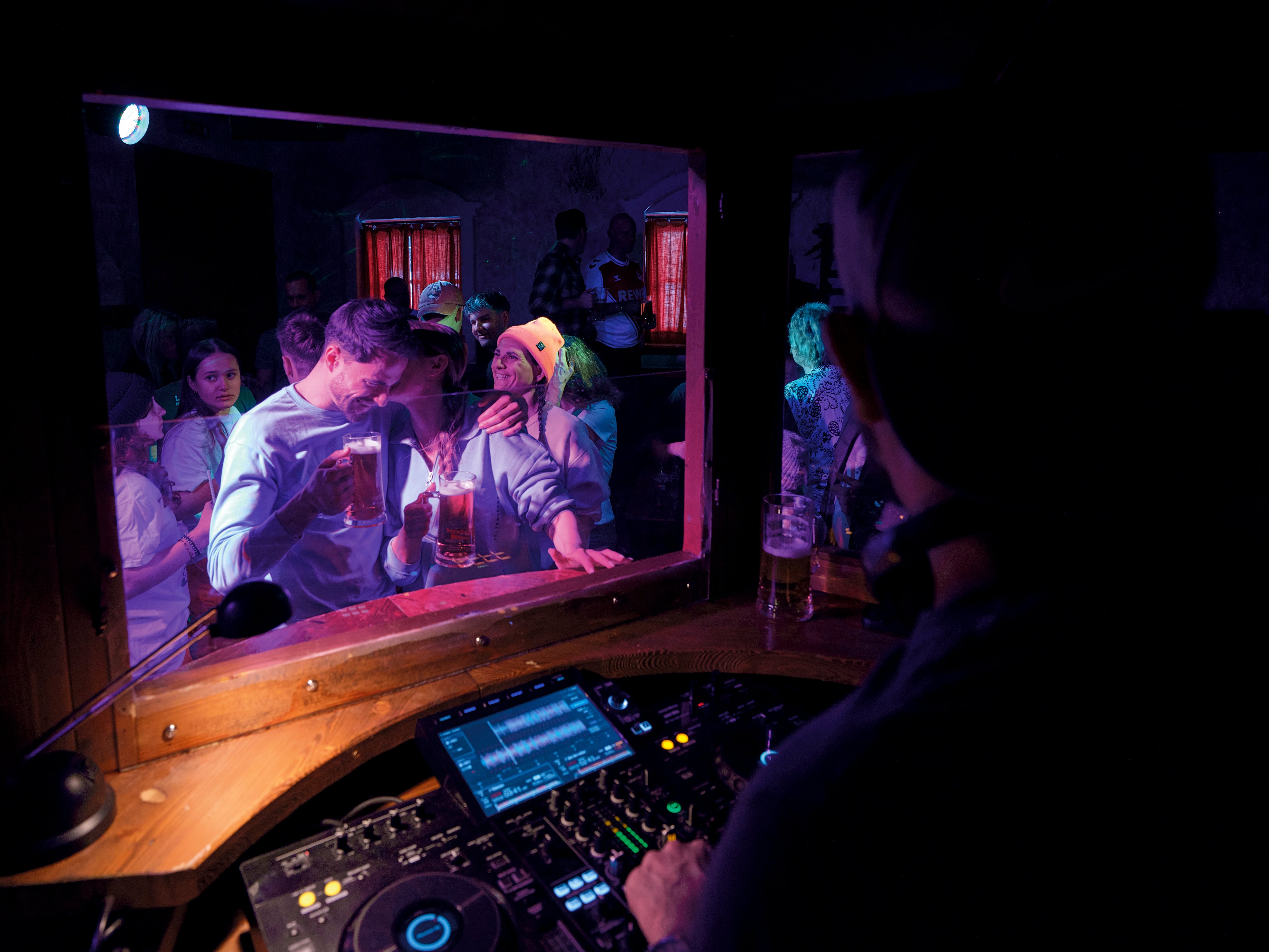 DJ beim Auflegen in einem Aldiana Club, Party mit Gästen in dunkler Atmosphäre