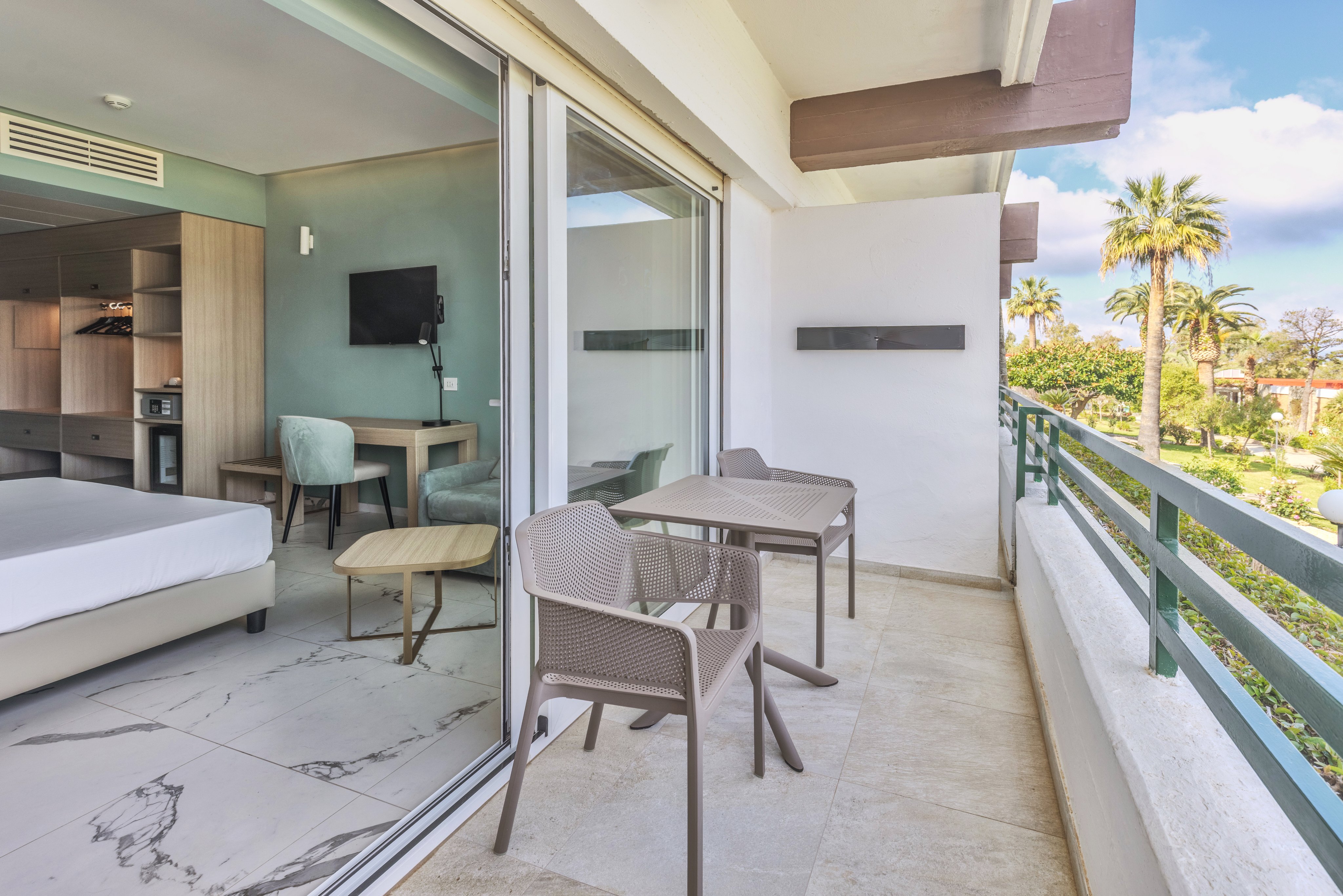 Balkonansicht mit Sitzgelegenheiten, Blick auf Pool und Palmen, Ferien im Premium Cluburlaub