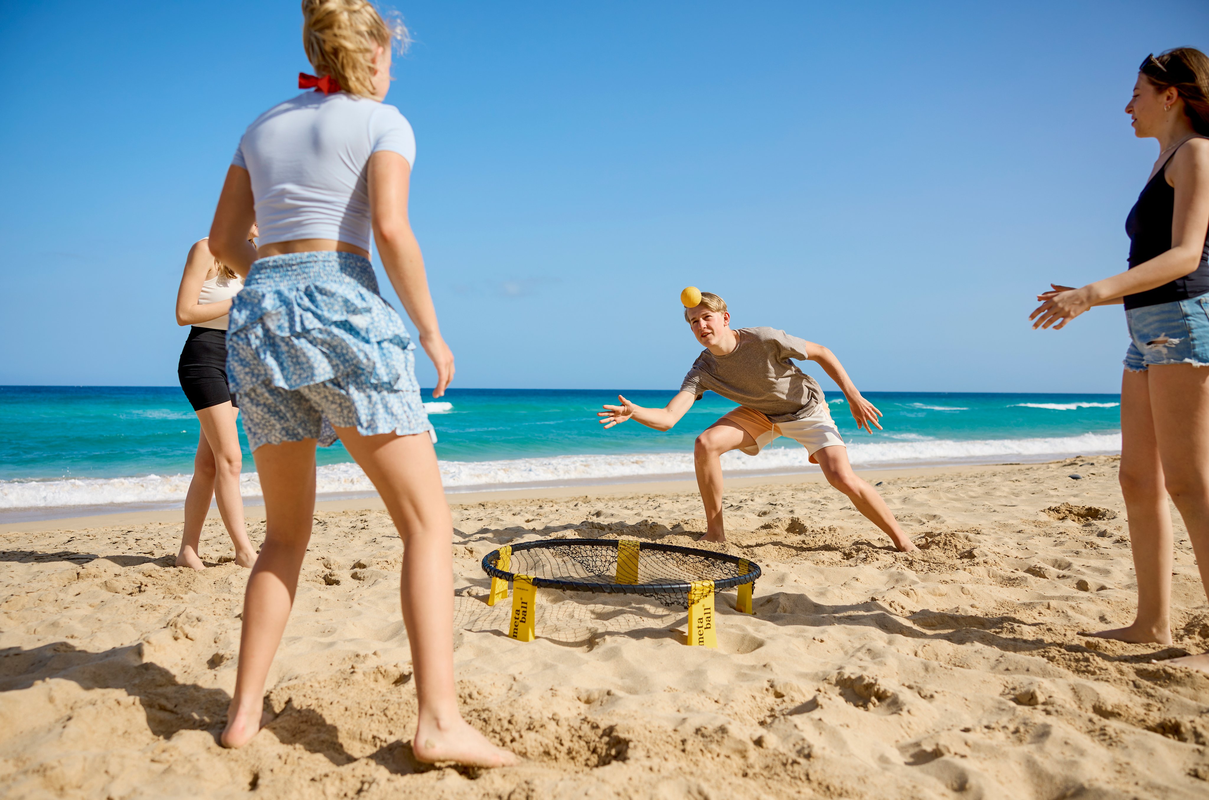 Menschen spielen Beach-Volleyball am Strand im sonnigen Urlaubsambiente