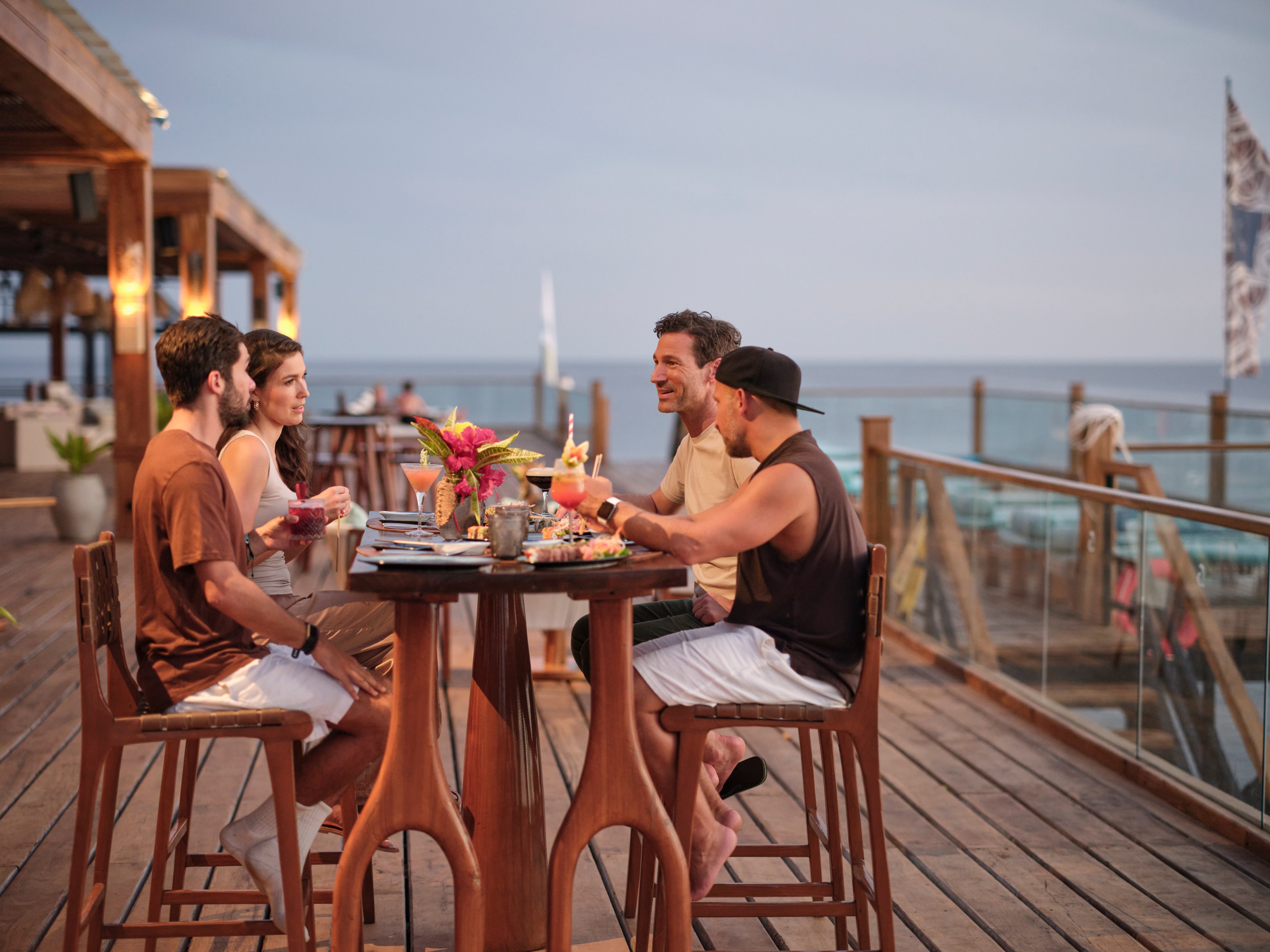 Menschen genießen ein Abendessen auf einer Holzterrasse mit Meerblick bei Aldiana Premium Cluburlaub