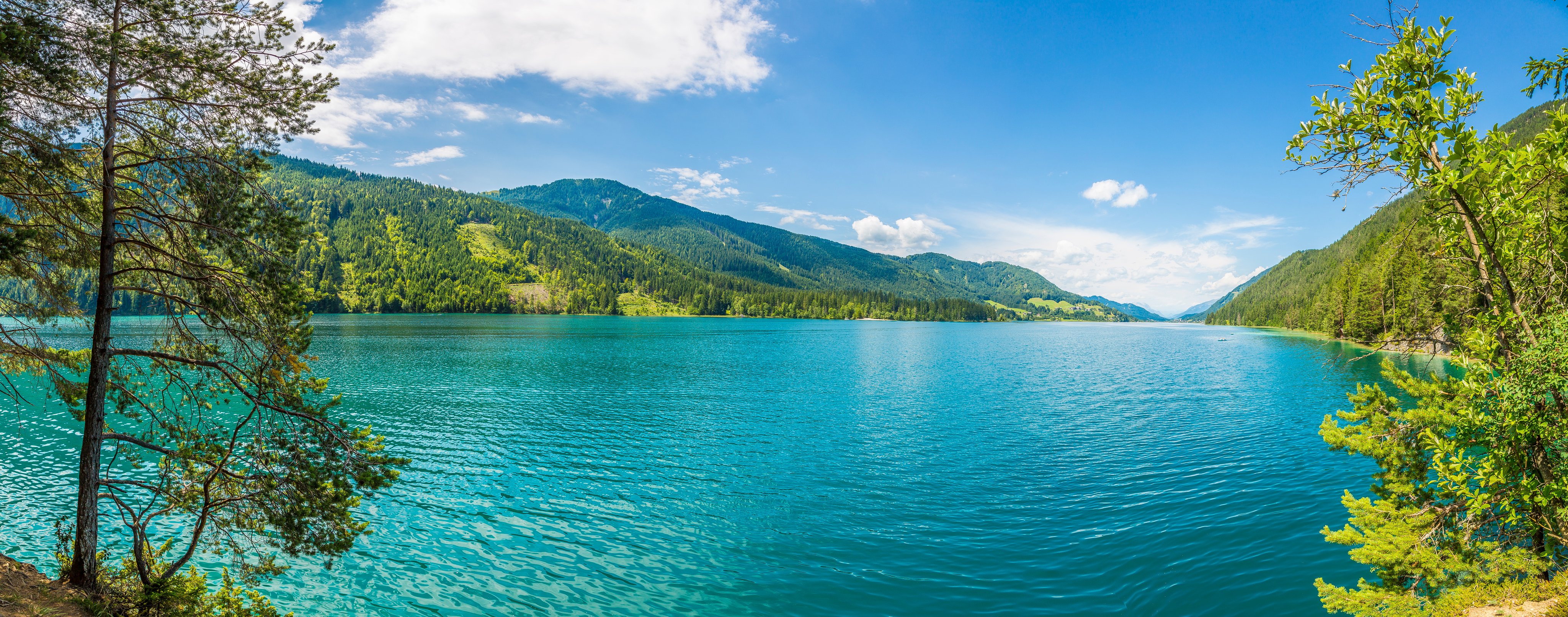 Ein ruhiger See vor grünen Bergen mit blauem Himmel, ideal für Premium Cluburlaub