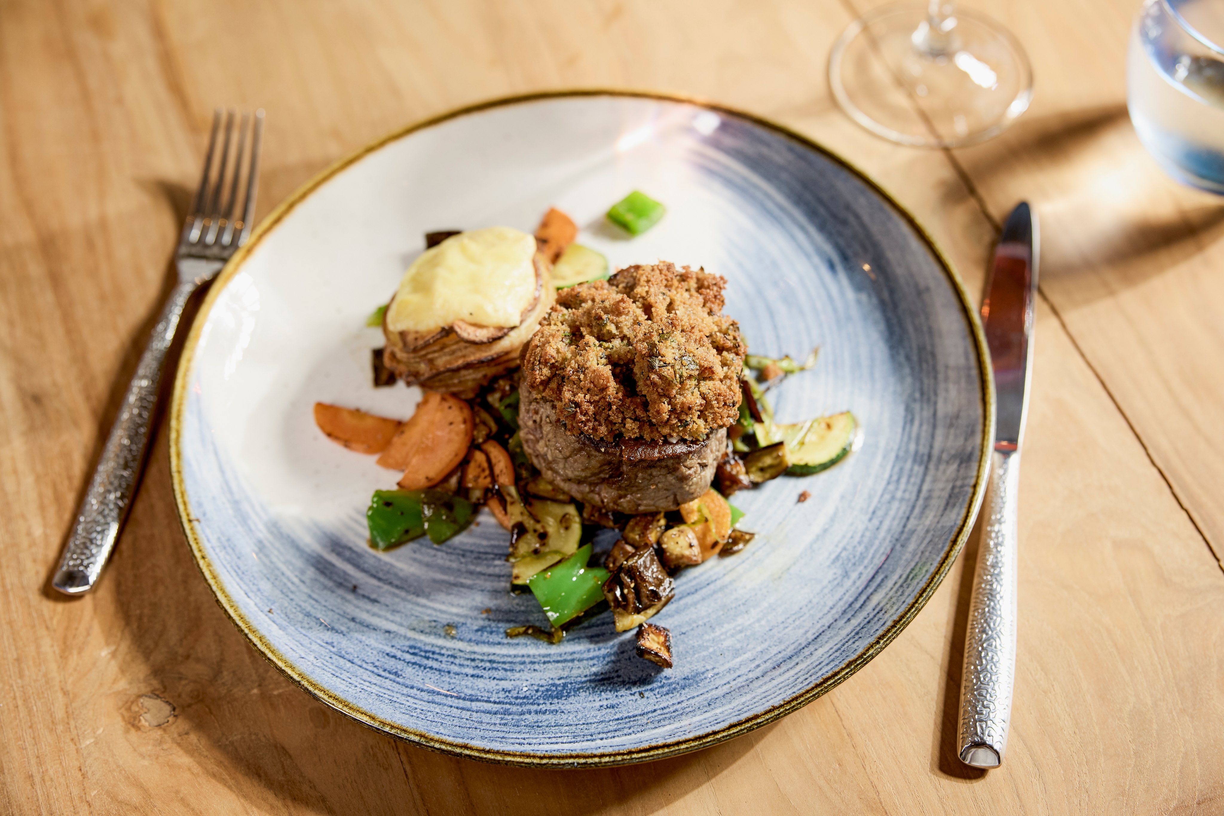 Ein edles Hauptgericht mit gebratenem Fleisch, Gemüse und Creme auf einem stilvollen Teller