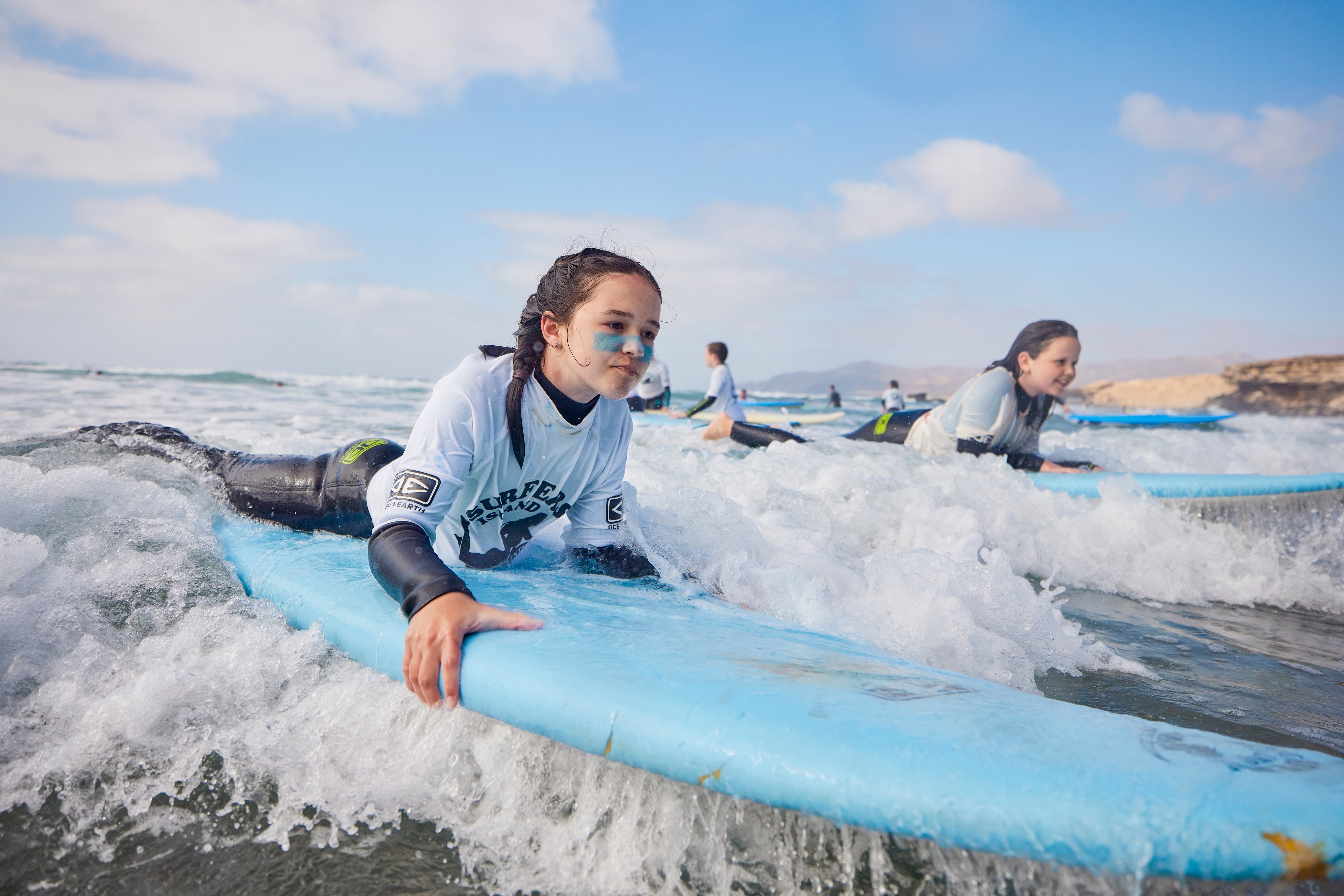 Junge Frau beim Surfen am Strand, ansprechende Kulisse, warmes Wetter, blauer Himmel