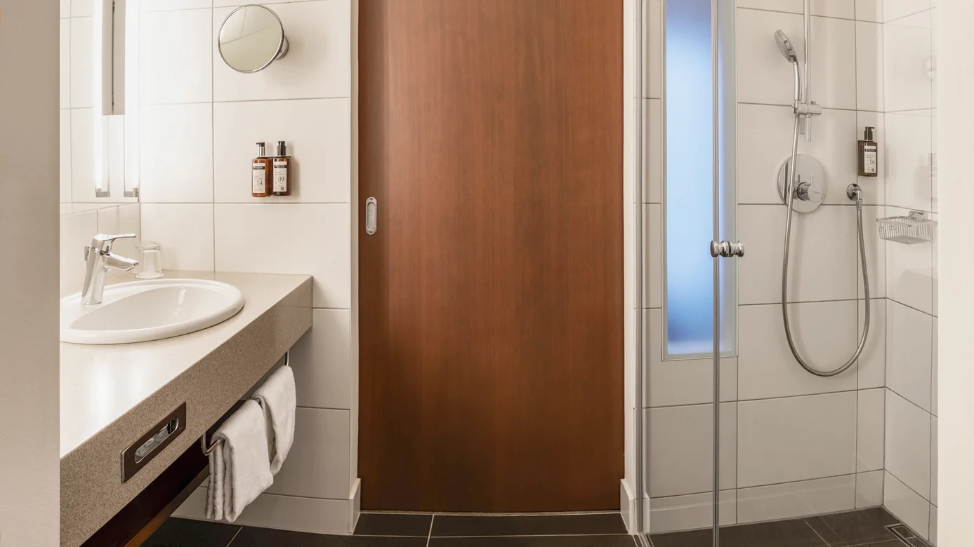 Badezimmer mit Waschbecken Dusche und Holzraumtür bei Aldiana Premium Cluburlaub