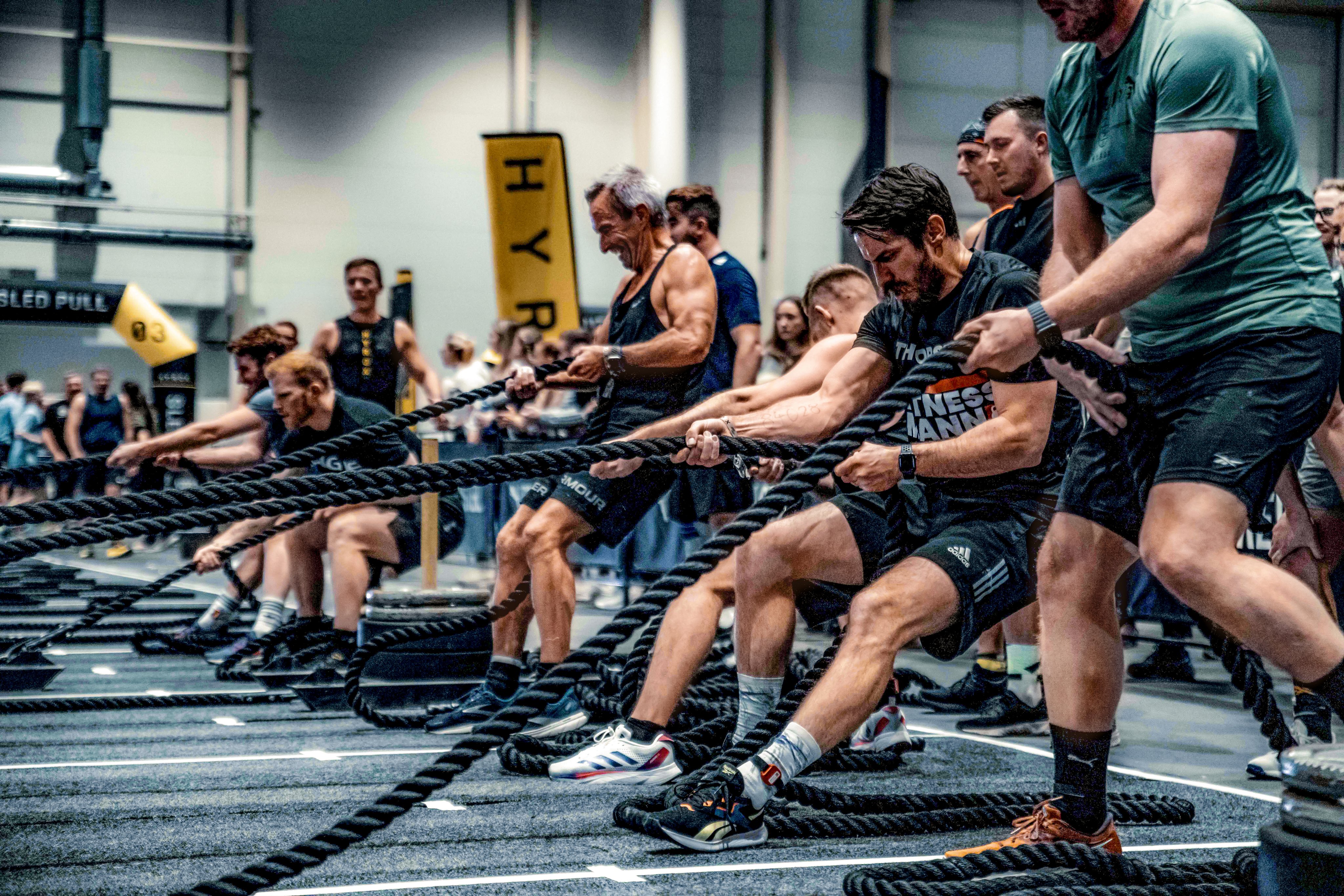 Menschen beim intensiven Seilziehen in einem Fitnessstudio, sichtbar in sportlicher Kleidung