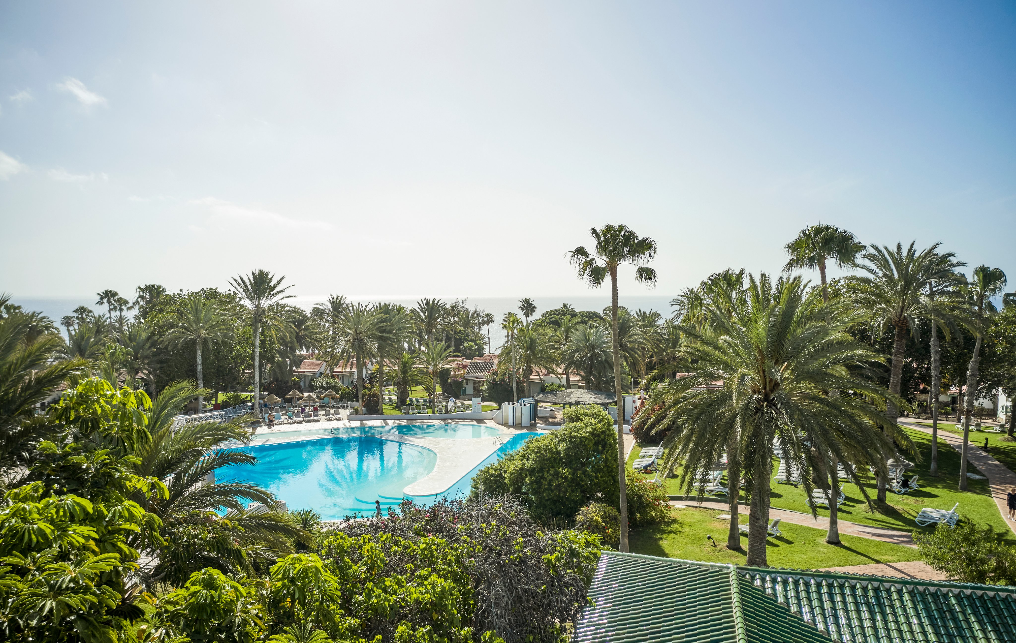 Blick auf einen luxuriösen Hotelpoolbereich mit Palmen und Meerblick bei Aldiana