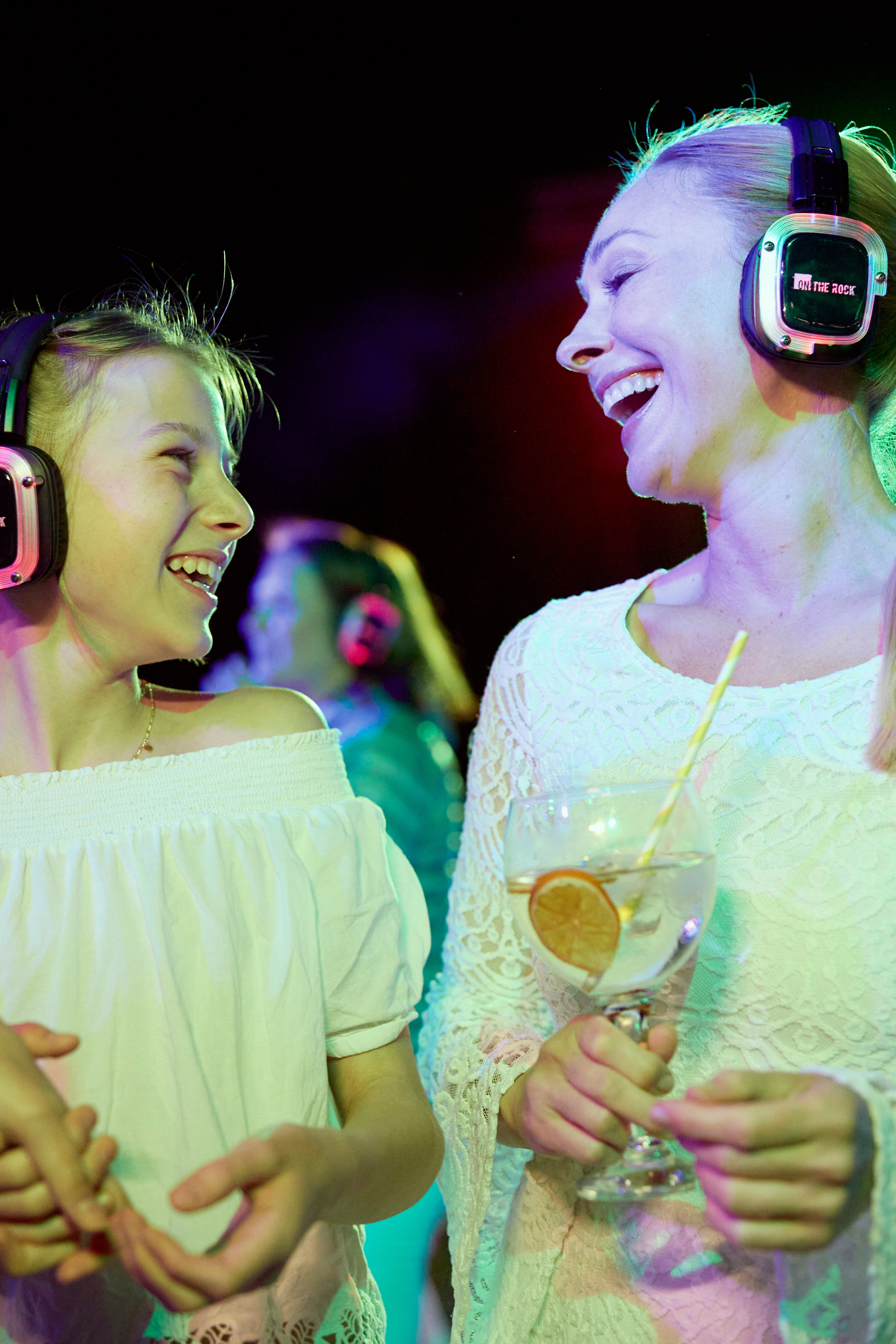 Zwei Frauen mit Kopfhörern und Getränk bei einem festlichen Cluburlaub von Aldiana