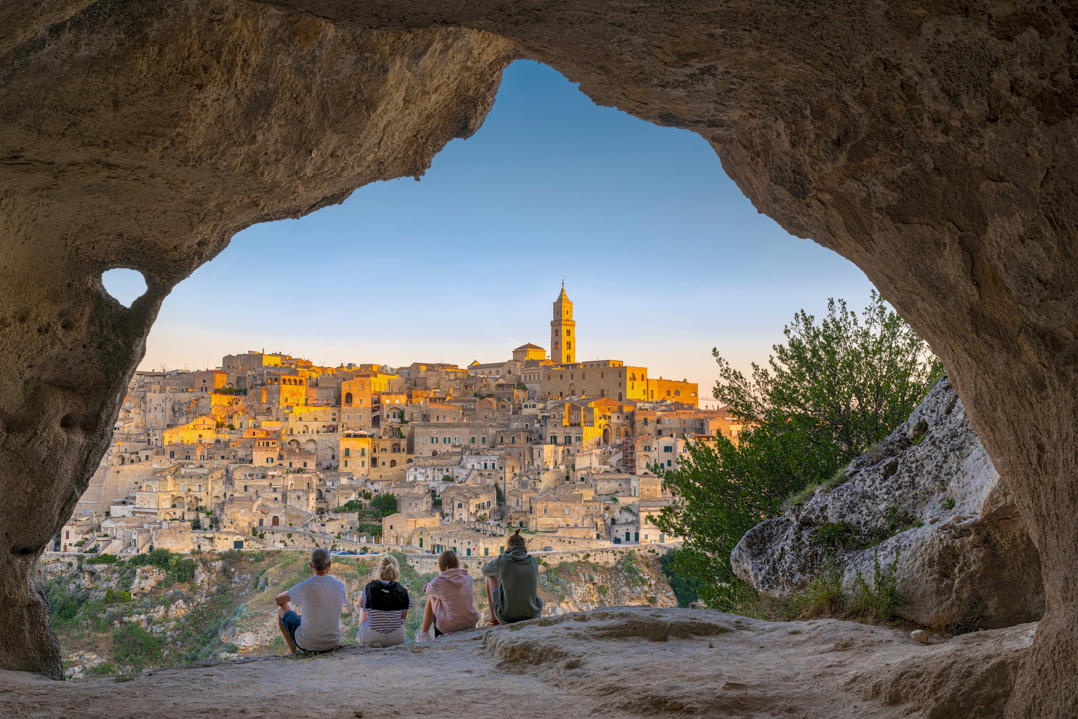 Blick auf die Altstadt von Matera mit vier erholsamen Touristen bei Sonnenuntergang