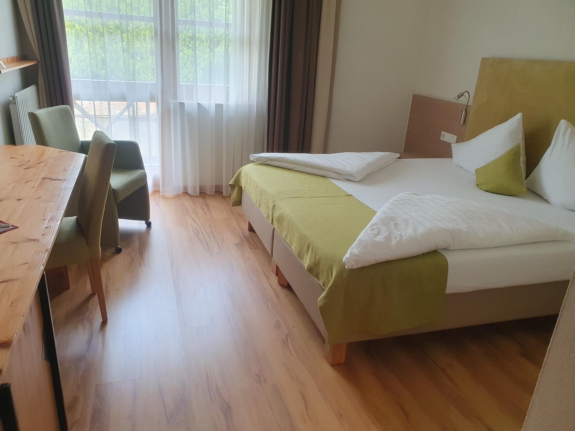 Doppelzimmer bei Aldiana mit Bett, Stühlen und Blick auf Balkon mit Fenster