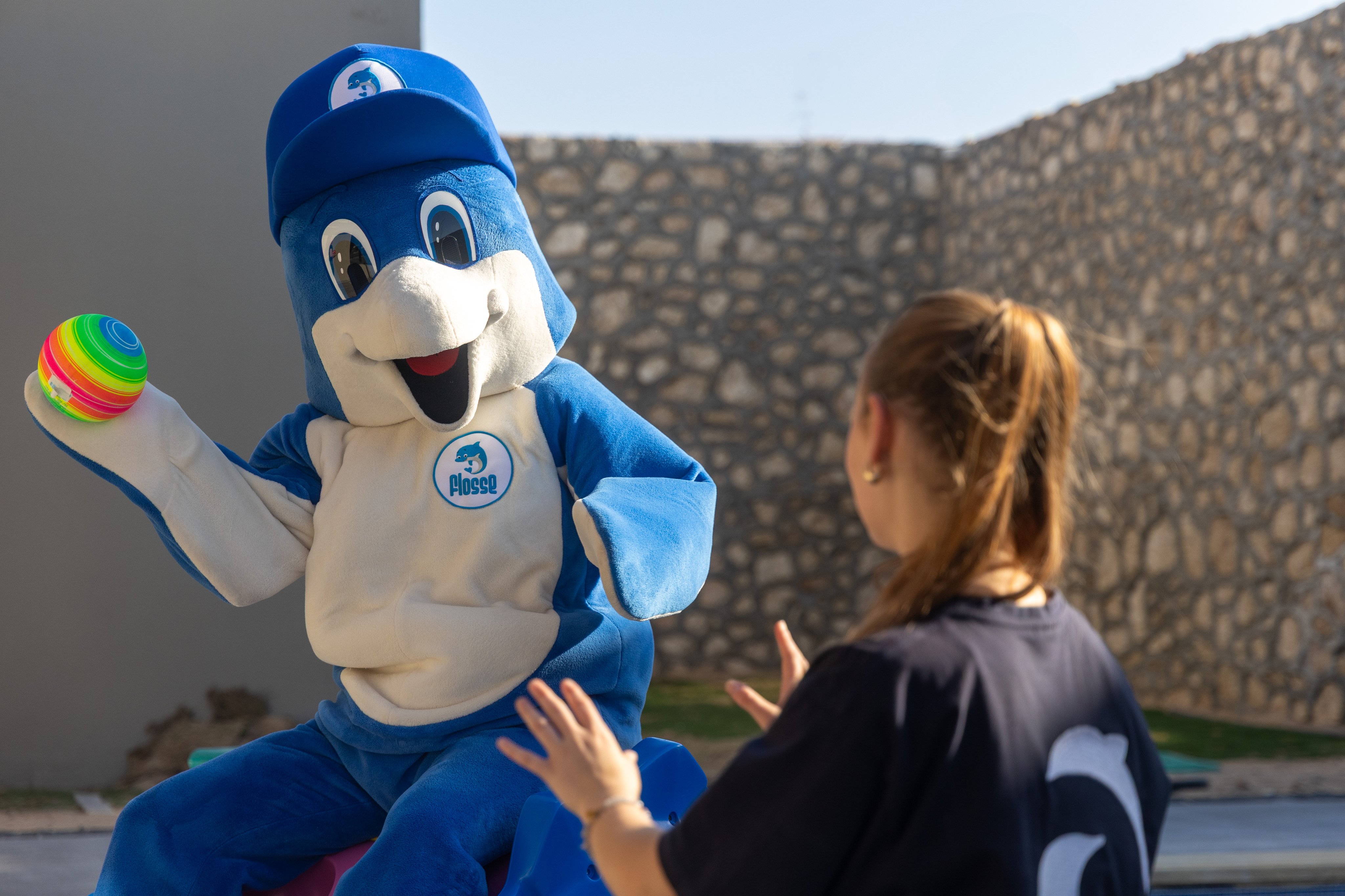 Freizeitpark mit Mascot und Besucherin im sonnigen Außenbereich.