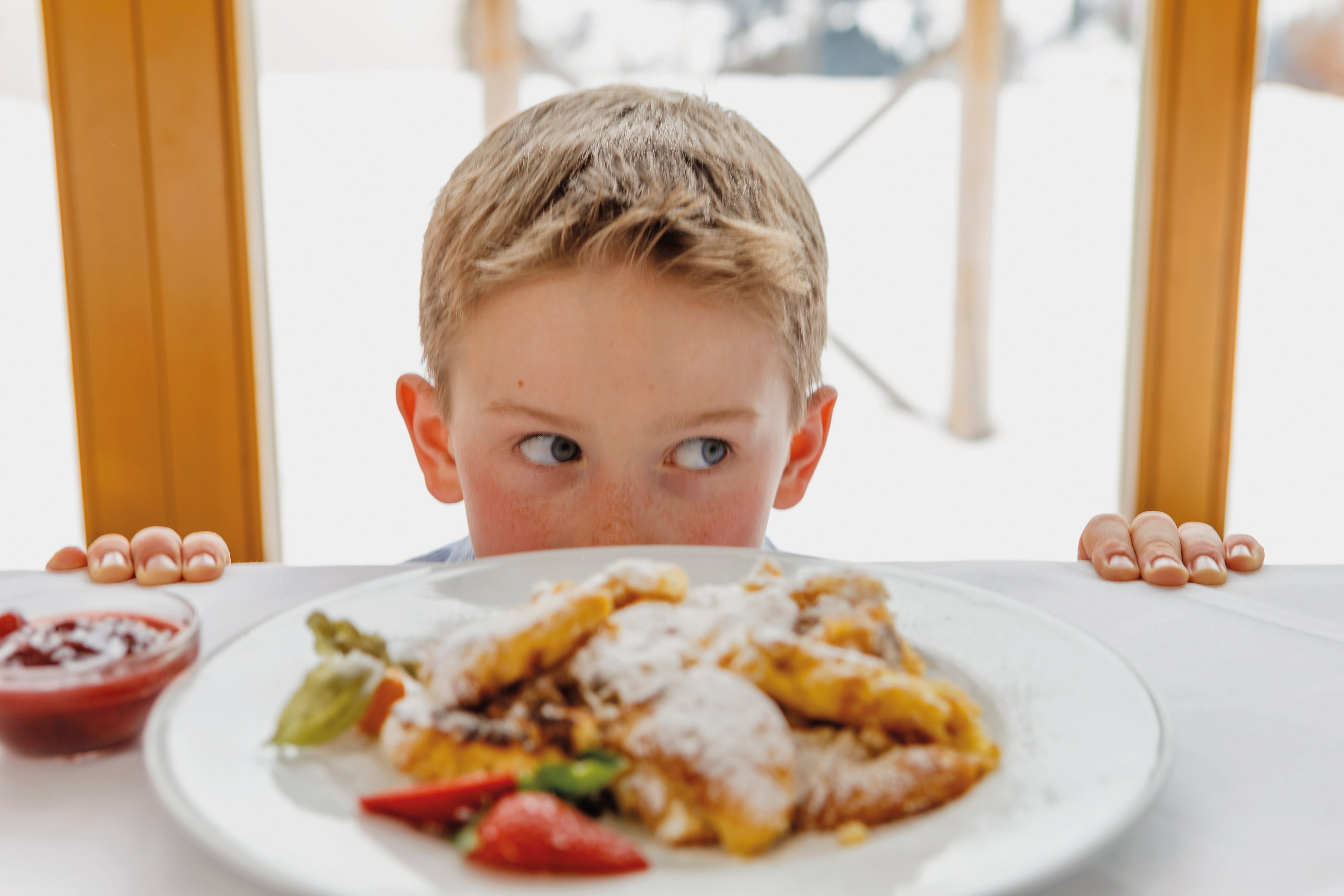 Ein Kind genießt ein Premium Cluburlaub-Erlebnis bei Aldiana mit leckerem Essen am Tisch