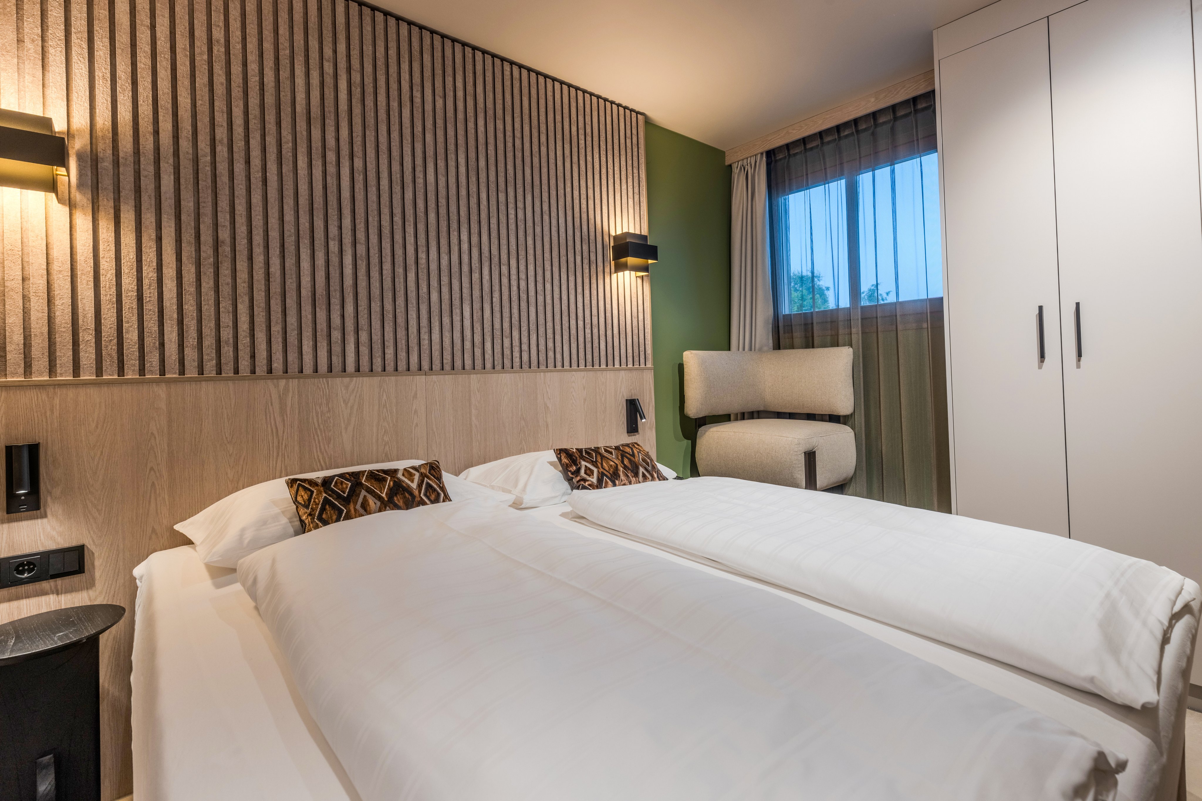 Modern Hotelzimmer von Aldiana mit Doppelbett, Sitzgelegenheit und Fenster mit Sicht in die Natur